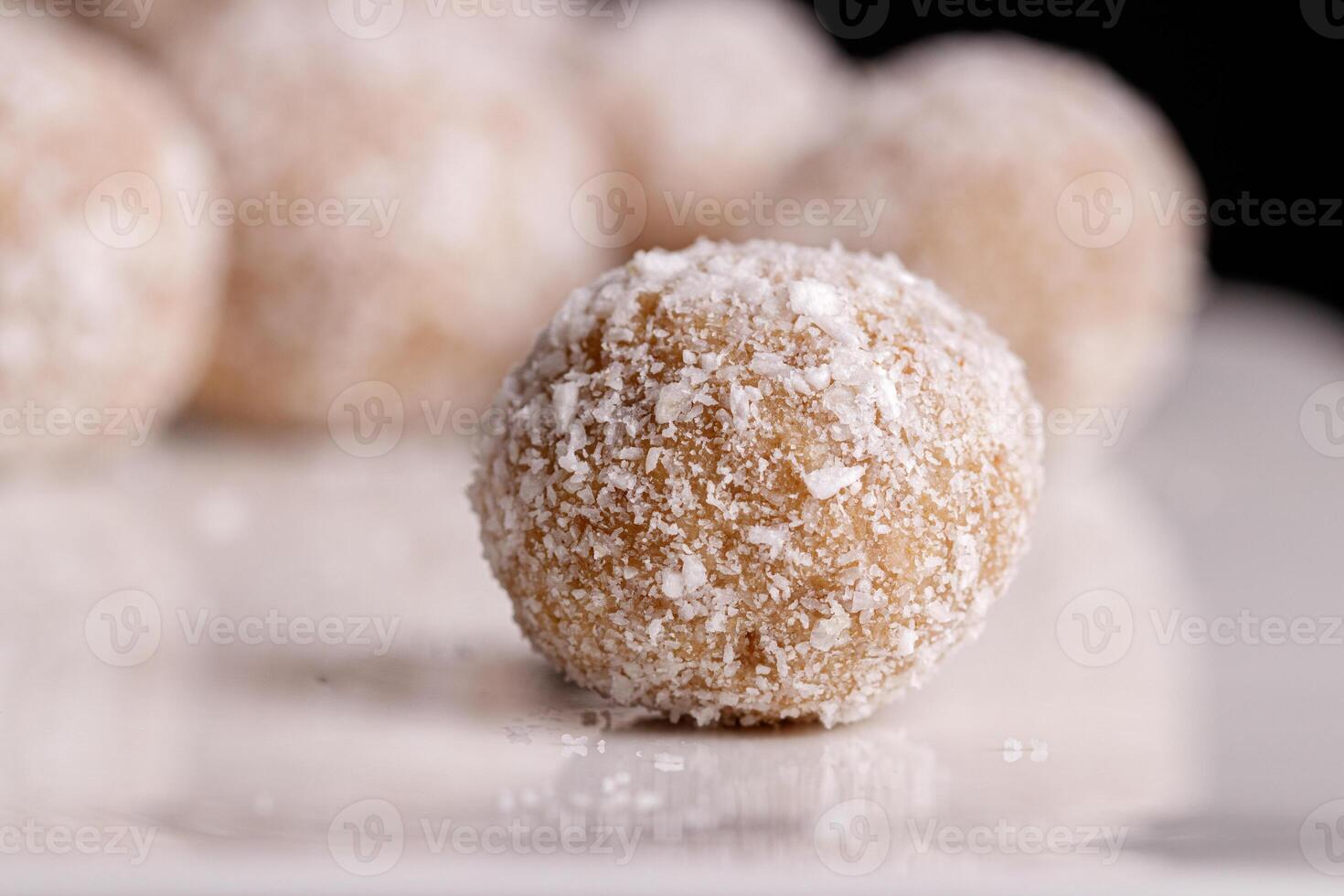 Beautiful sweets with coconut on a white plate on a black background photo