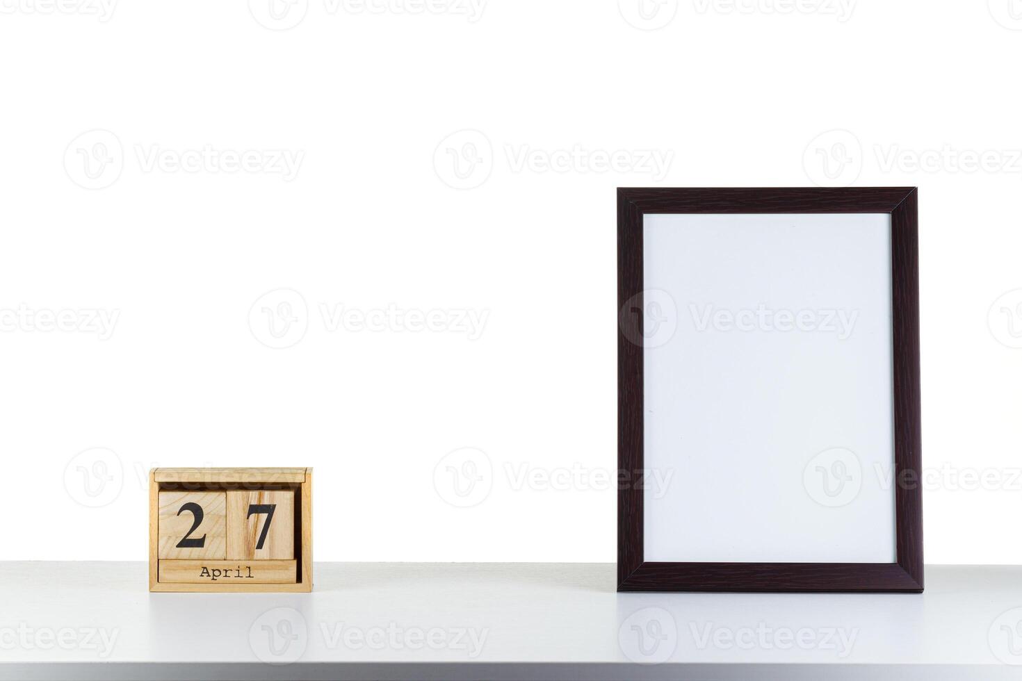 Wooden calendar 27 april with frame for photo on white table and background