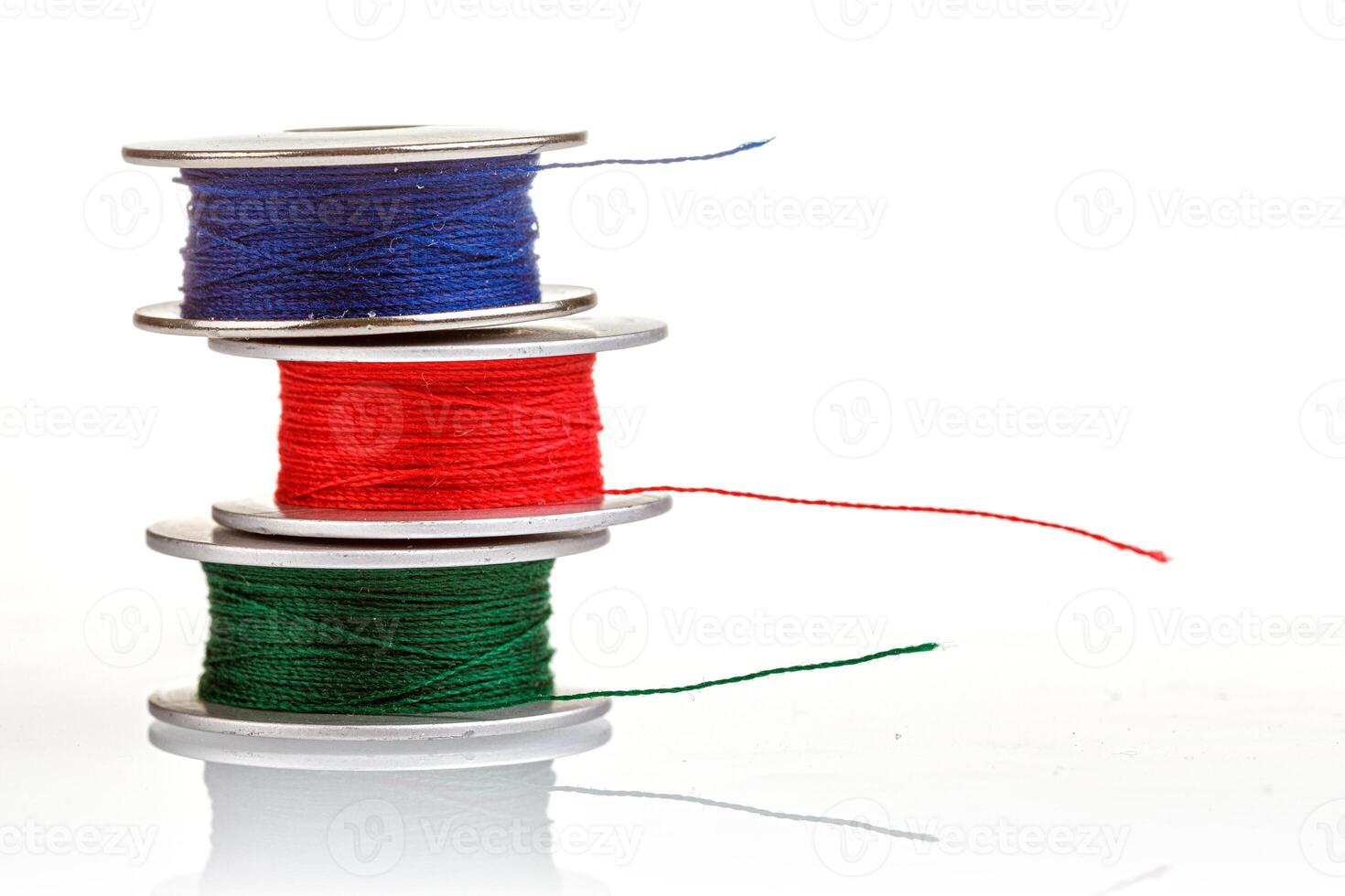 spools of thread in blue, red, green colors on a white background photo