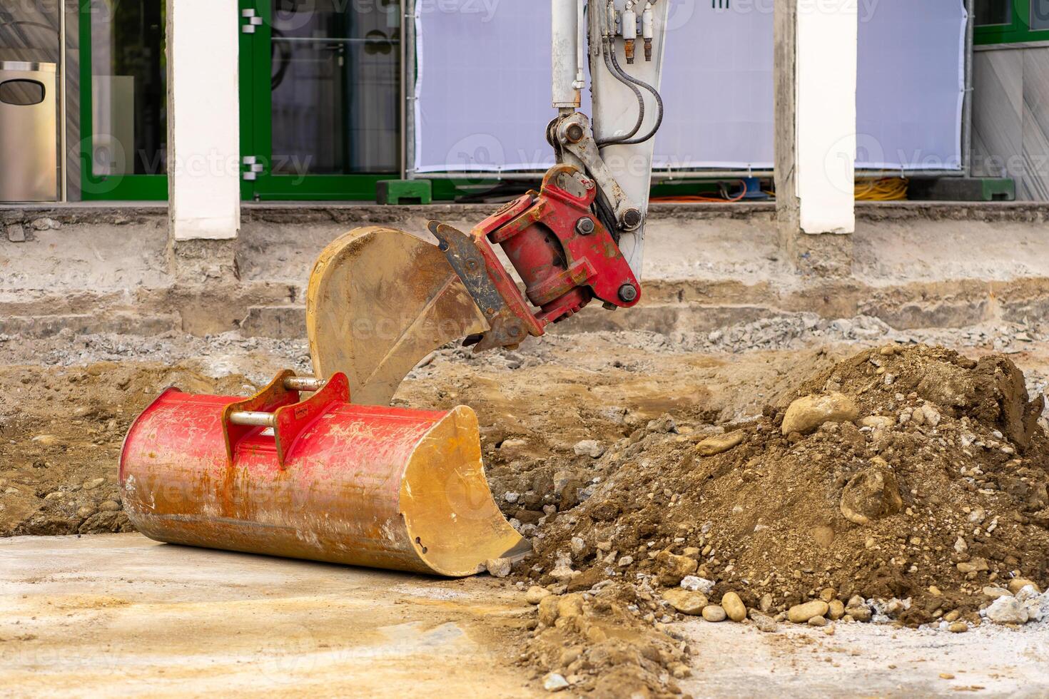 Excavator bucket collects soil and old asphalt at a construction site photo