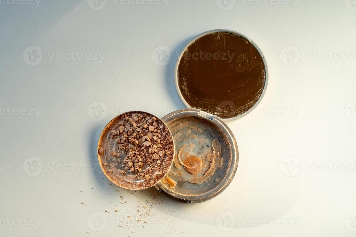 Broken palette with highlighter on a white table. Decorative cosmetics photo
