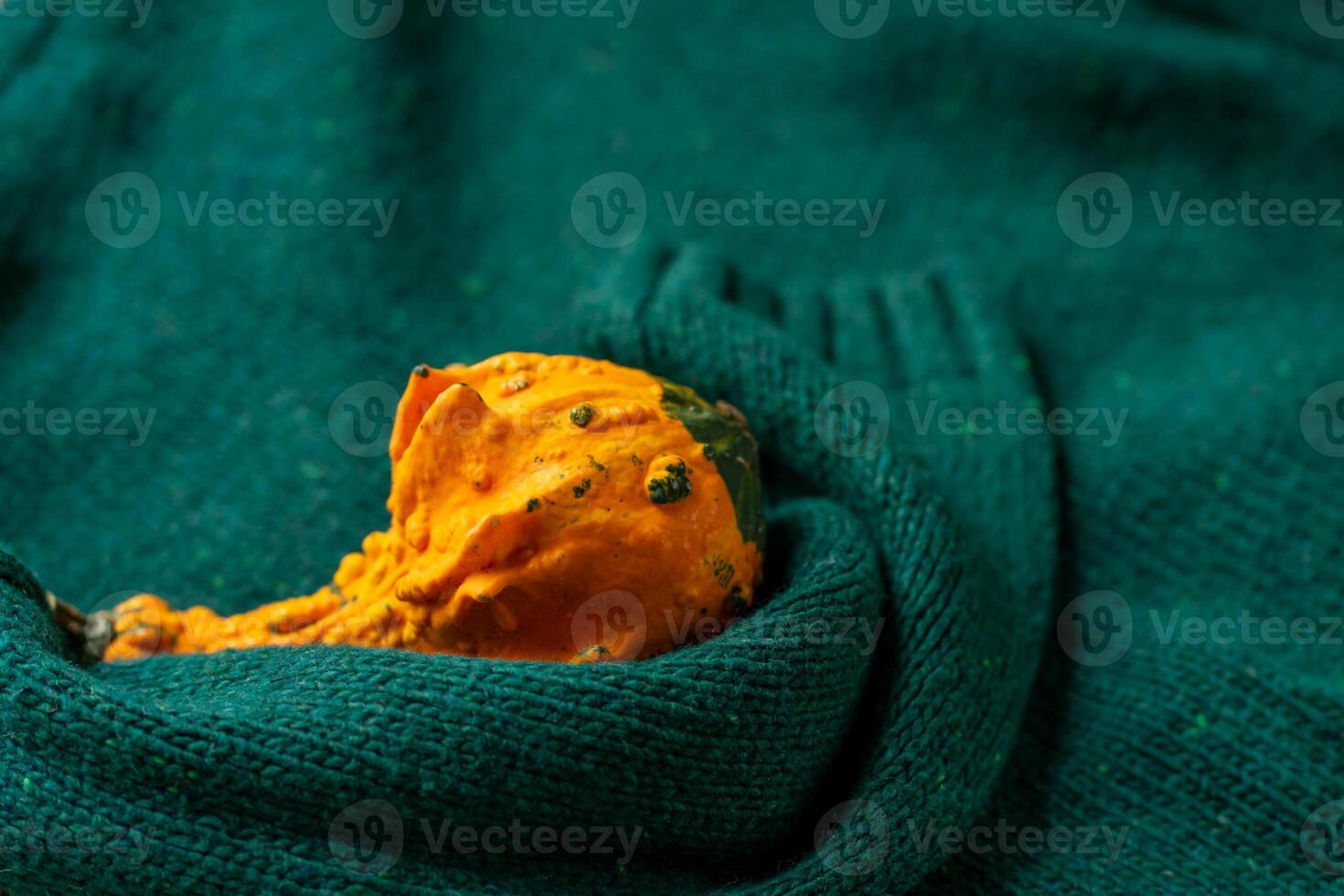 Orange pumpkin near a stack of knitted sweaters on a knitted blanket photo