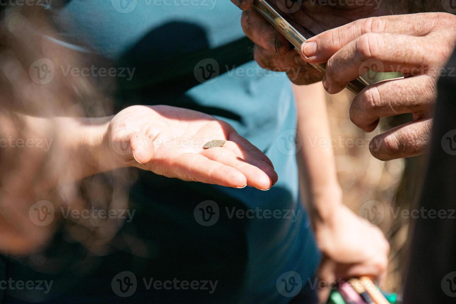 archaeologists taking a photograph with their mobile phones of an ancient coin that appeared in the dig. photo