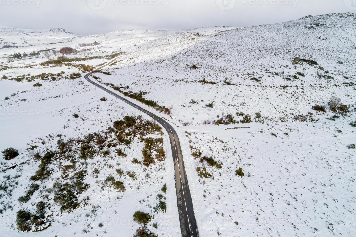 winding road through a snowy mountain landscape, scenic drive through snowy mountain peaks. Aerial view from a drone photo