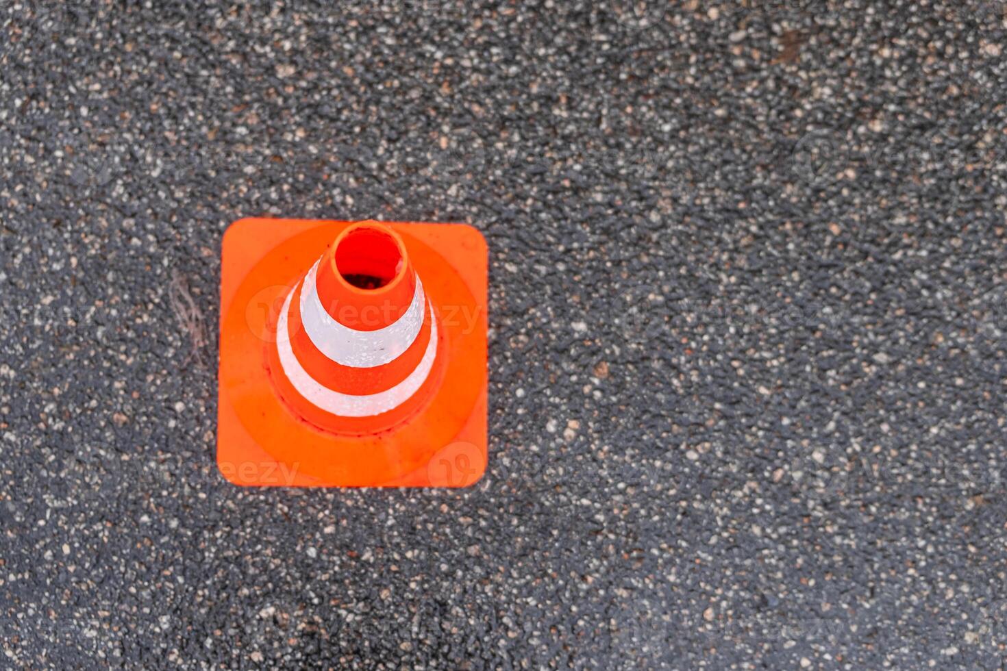 Striped orange cones on the asphalt road. Plastic orange cone on the road. Construction cones marking part of road with a layer of fresh asphalt. photo