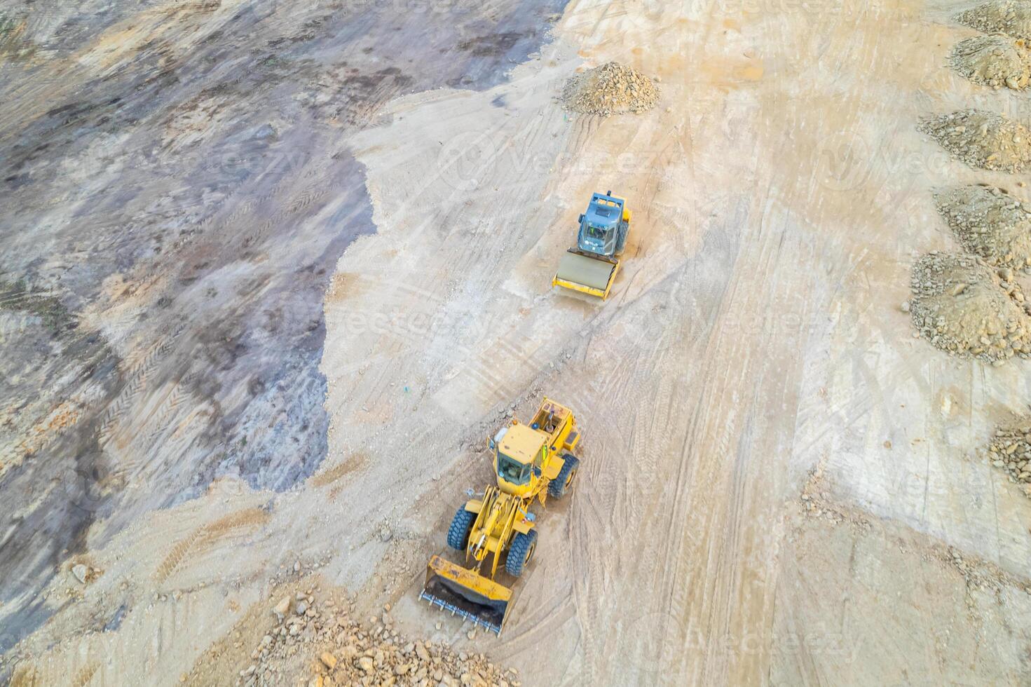 heavy machinery on a construction site, a bulldozer and a steamroller preparing the terrain, aerial view with a drone. photo