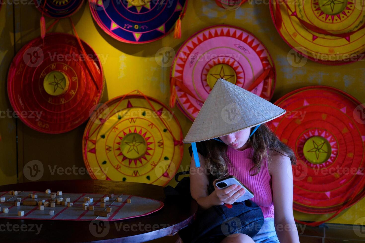 Traditional vietnamese hat. holds a phone in his hands, sits. Travel to asia Girl in Vietnamese hat with phone photo