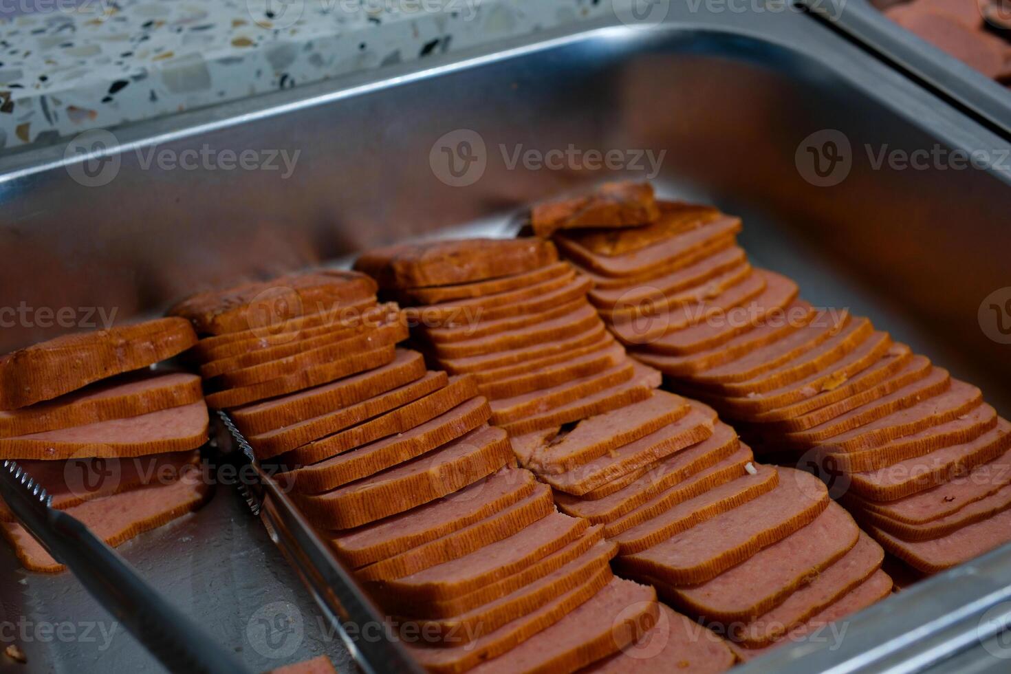 Block of Spam luncheon meat cut into slices on a cutting board. Knife is in the background. photo