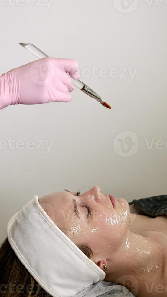 A professional beautician makes a Carboxing bone mask for the face and neck of a client of a carboxytherapy patient, close-up photo