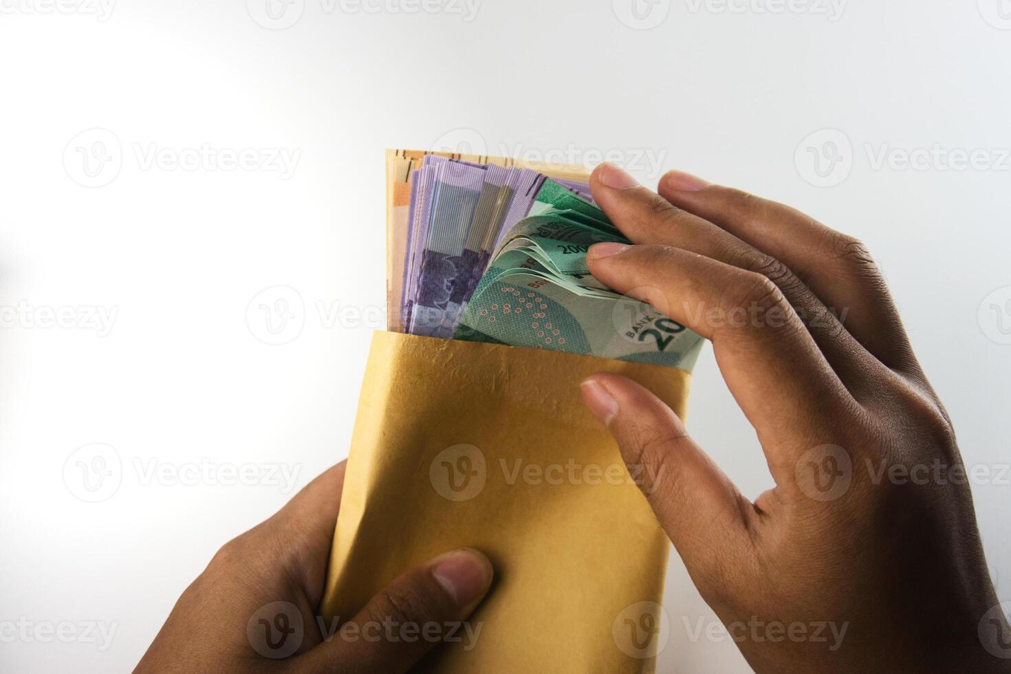 Hands Counting Colorful Banknotes Inserted in a Yellow Envelope on White Background photo