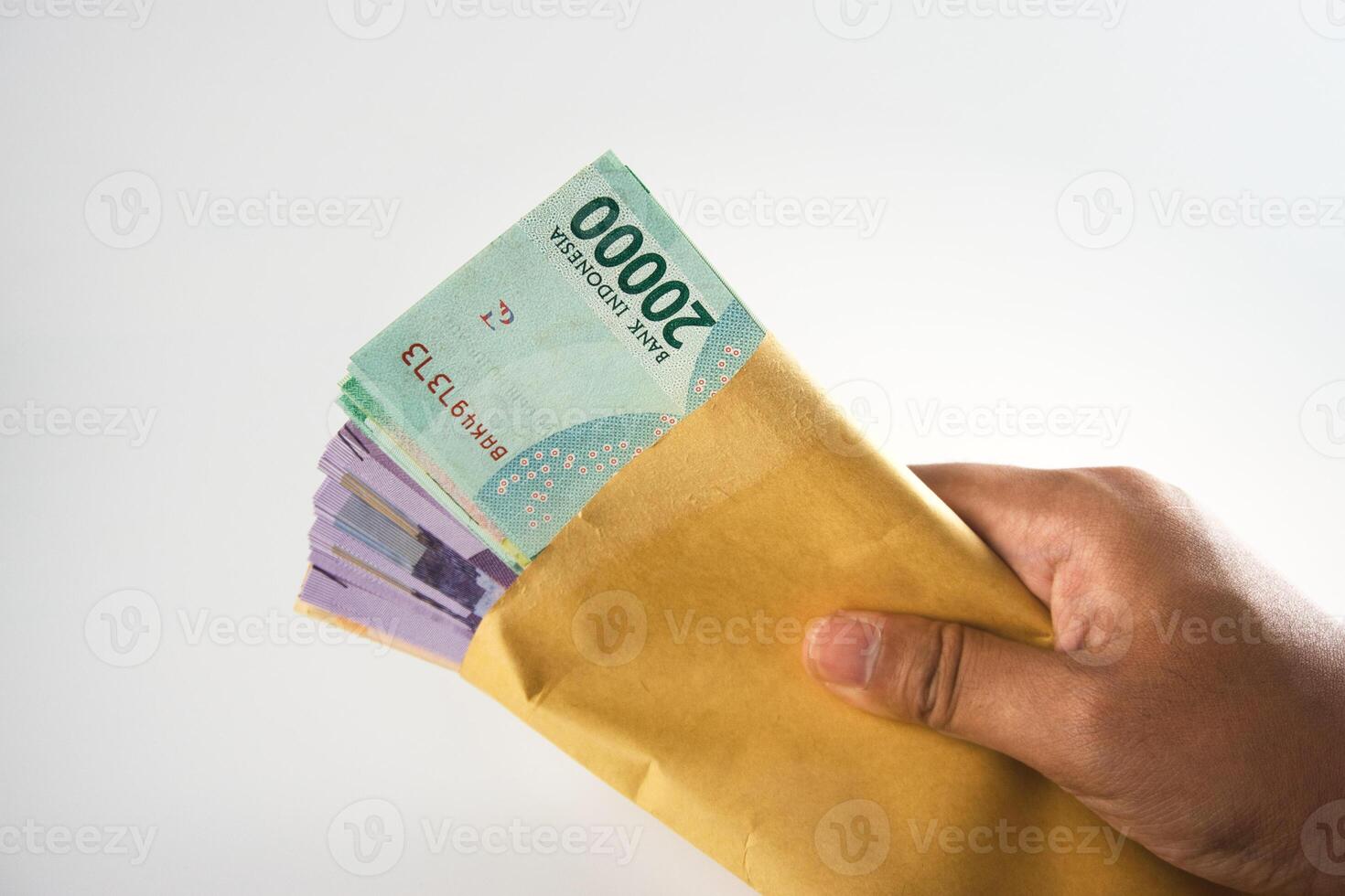Hand Holding an Envelope Filled with Indonesian Rupiah Banknotes photo