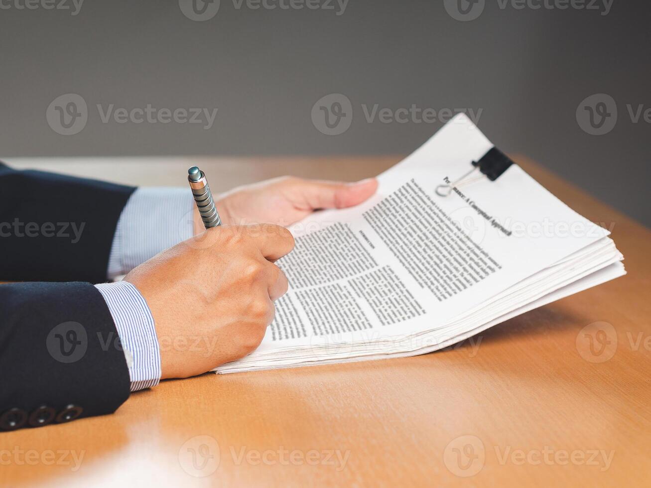 Close-up of a businessman signing on documents while sitting working in the office photo