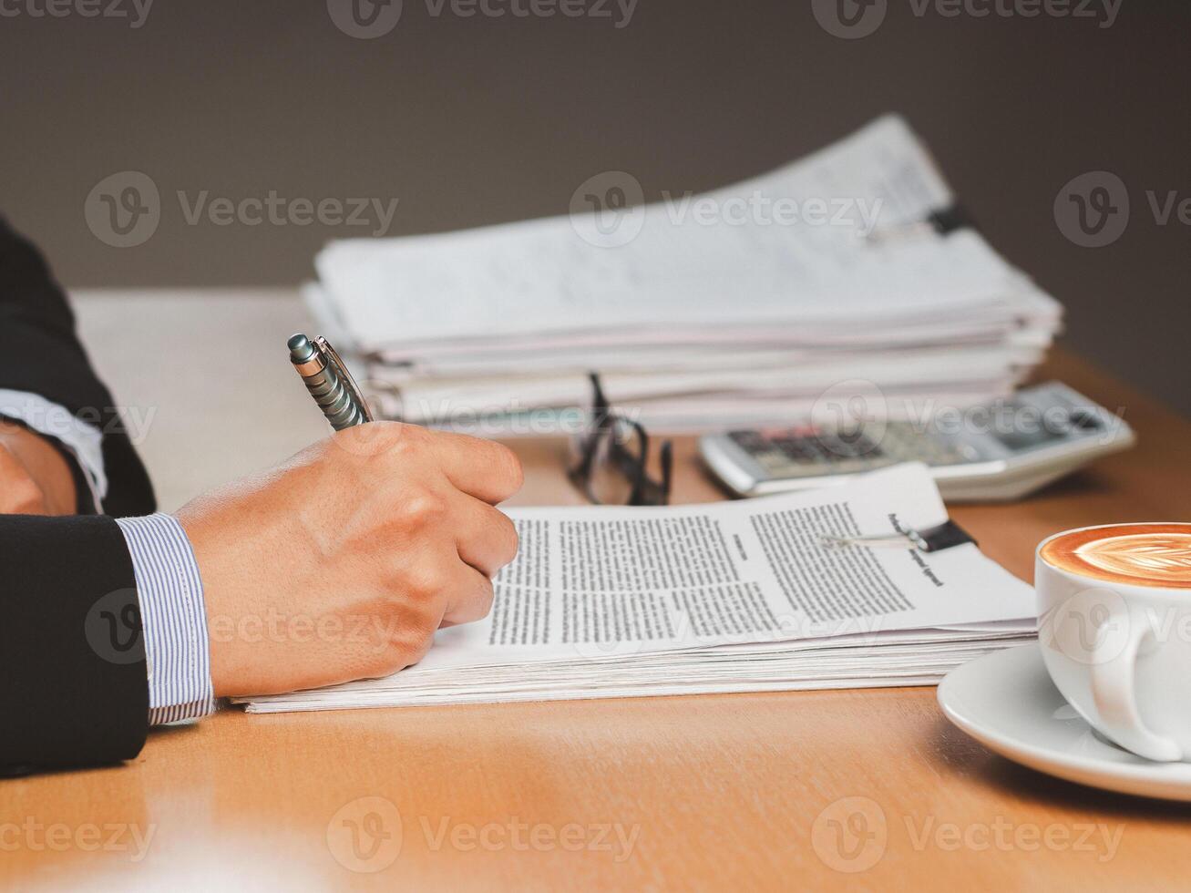 Close-up of a businessman signing on documents while sitting working in the office photo
