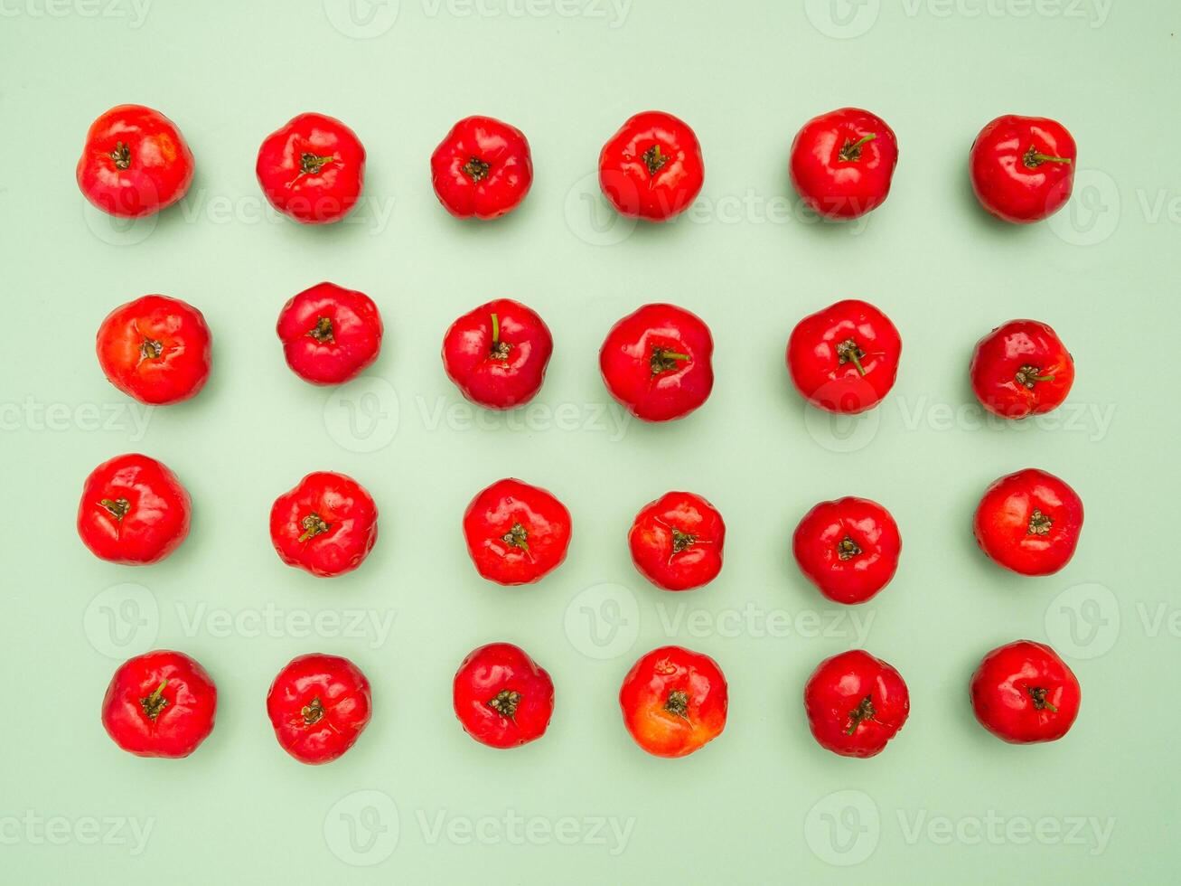 Ripe red acerola cherries isolated on a light green background photo