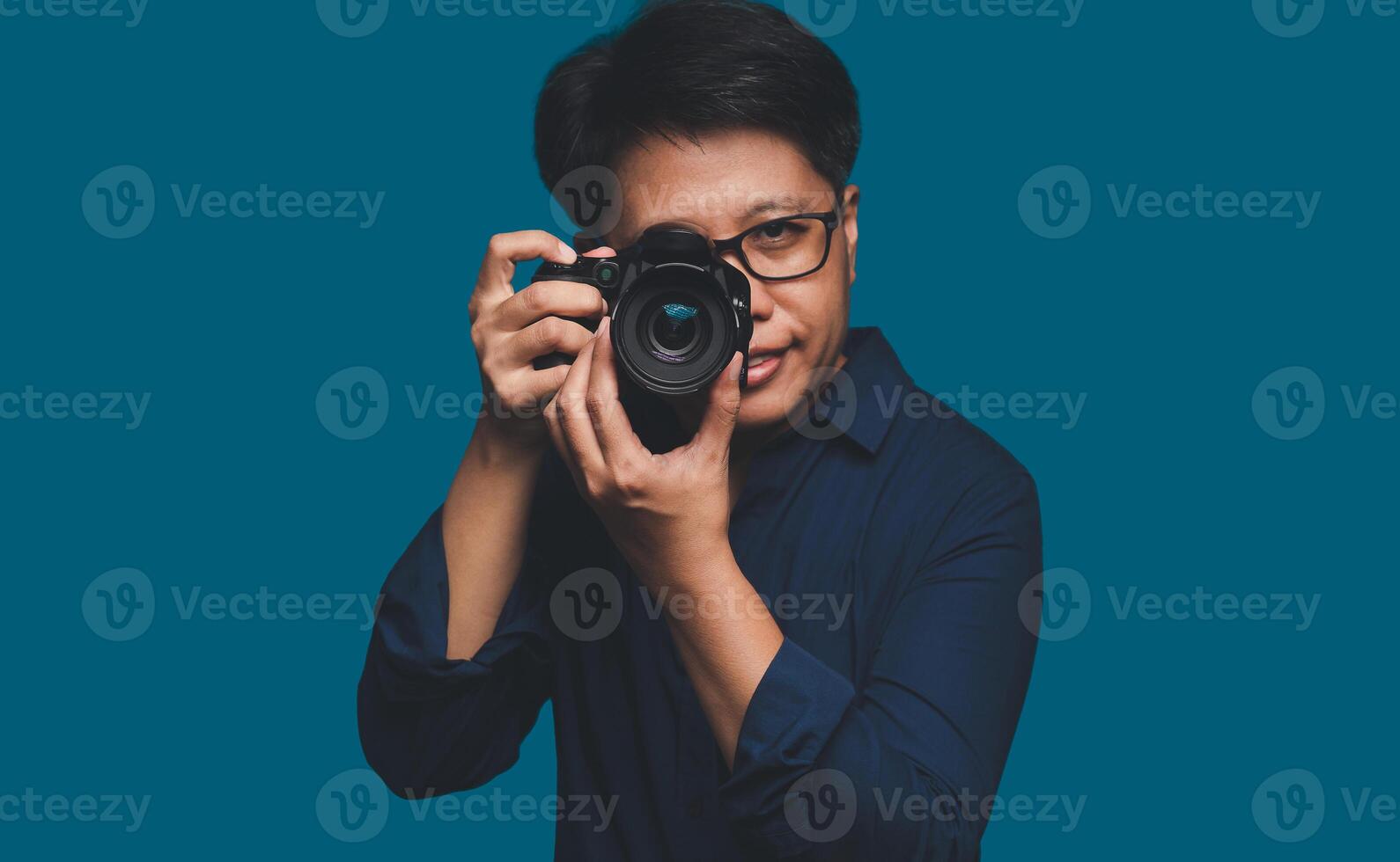 A Photographer holding a digital camera while standing on a blue background photo