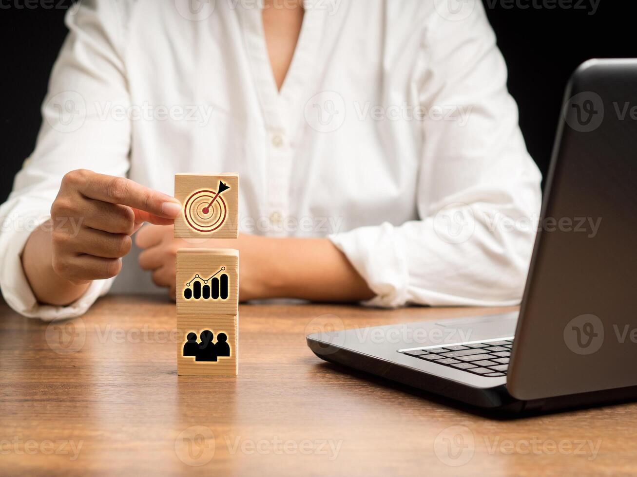 Close-up of hand businesswoman holding a wooden cube with icon business strategy while sitting in the office photo