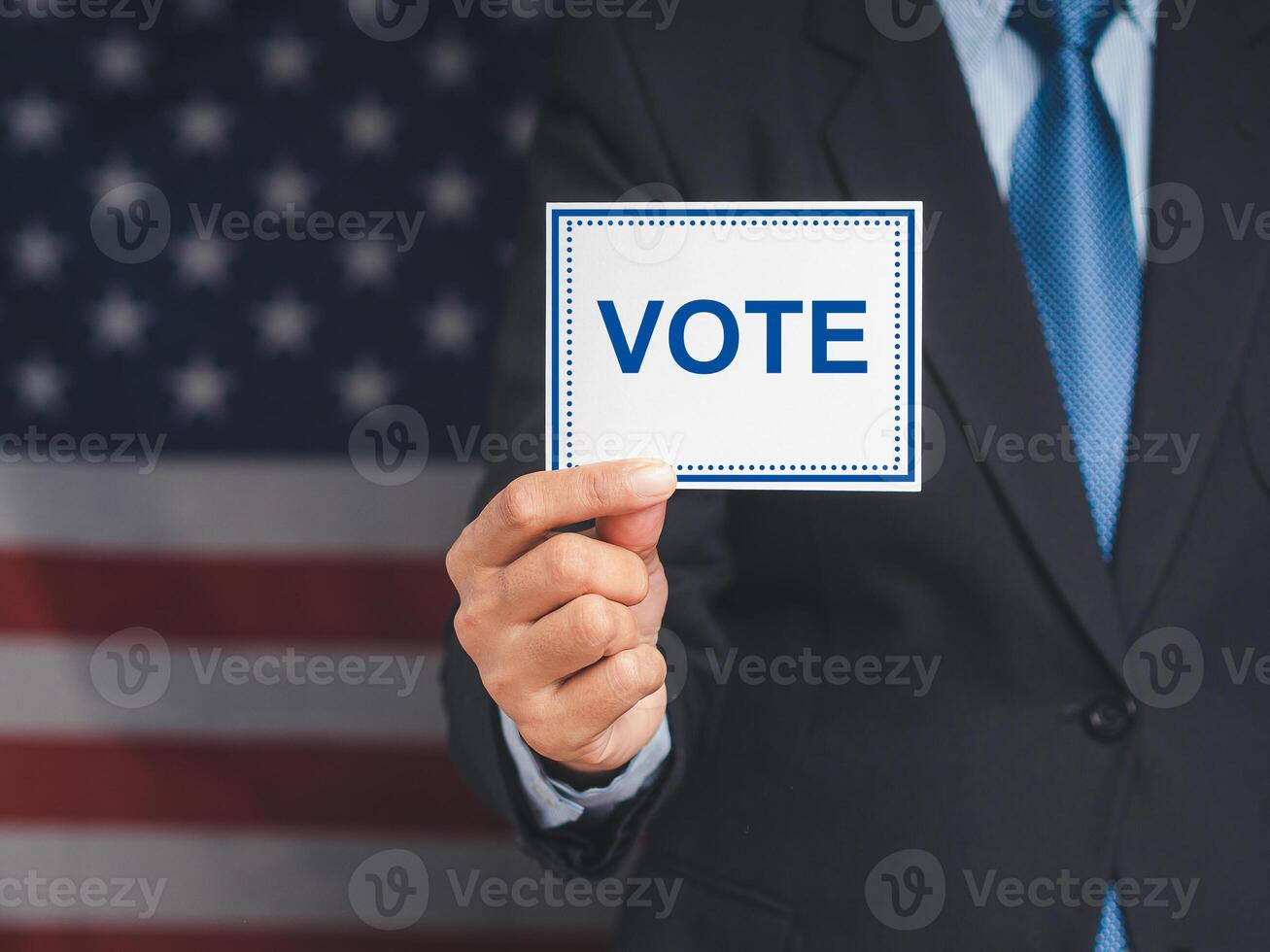 Close-up of hand voter holding paper with text VOTE while standing on the American flag background photo