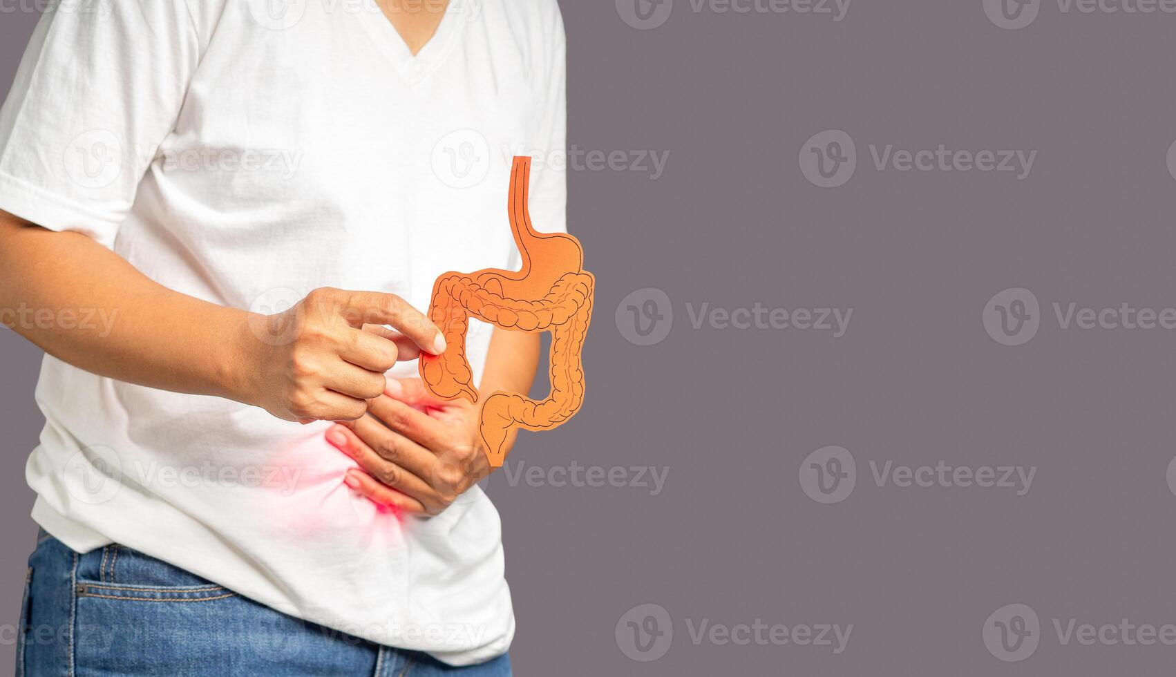 Hands holding a colon symbol and touching stomach painful suffering from stomach ache while standing on a gray background photo