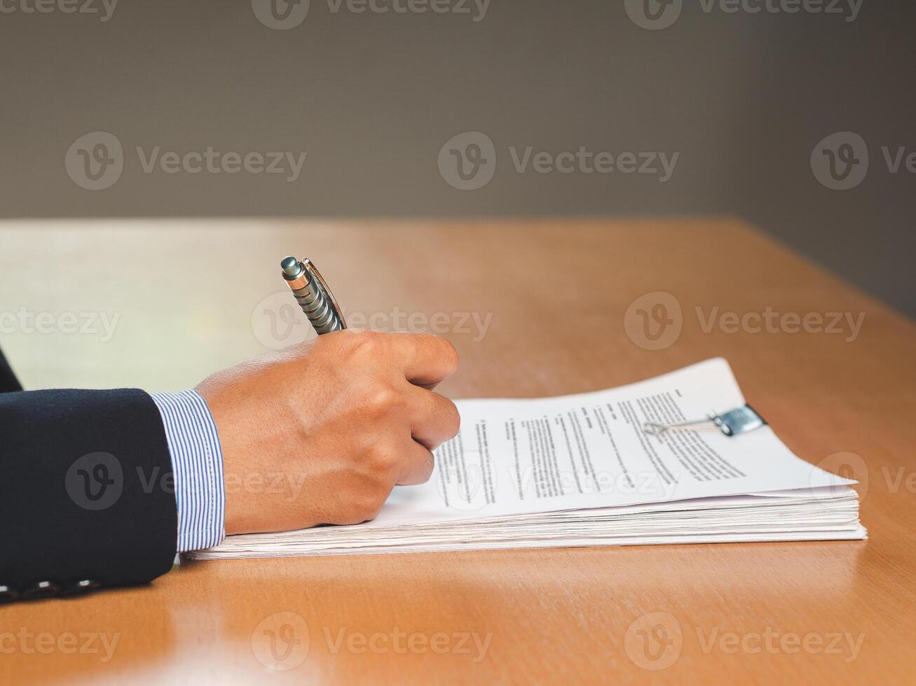 Close-up of a businessman signing on documents while sitting working in the office photo