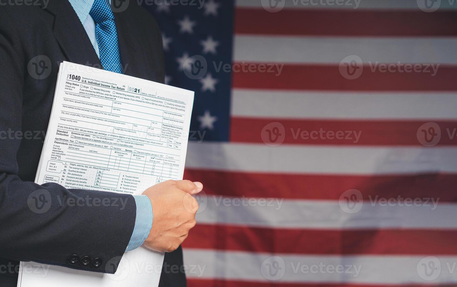 Businessman holding a tax form to prepare and complete an individual income tax payment form while standing on the American flag photo