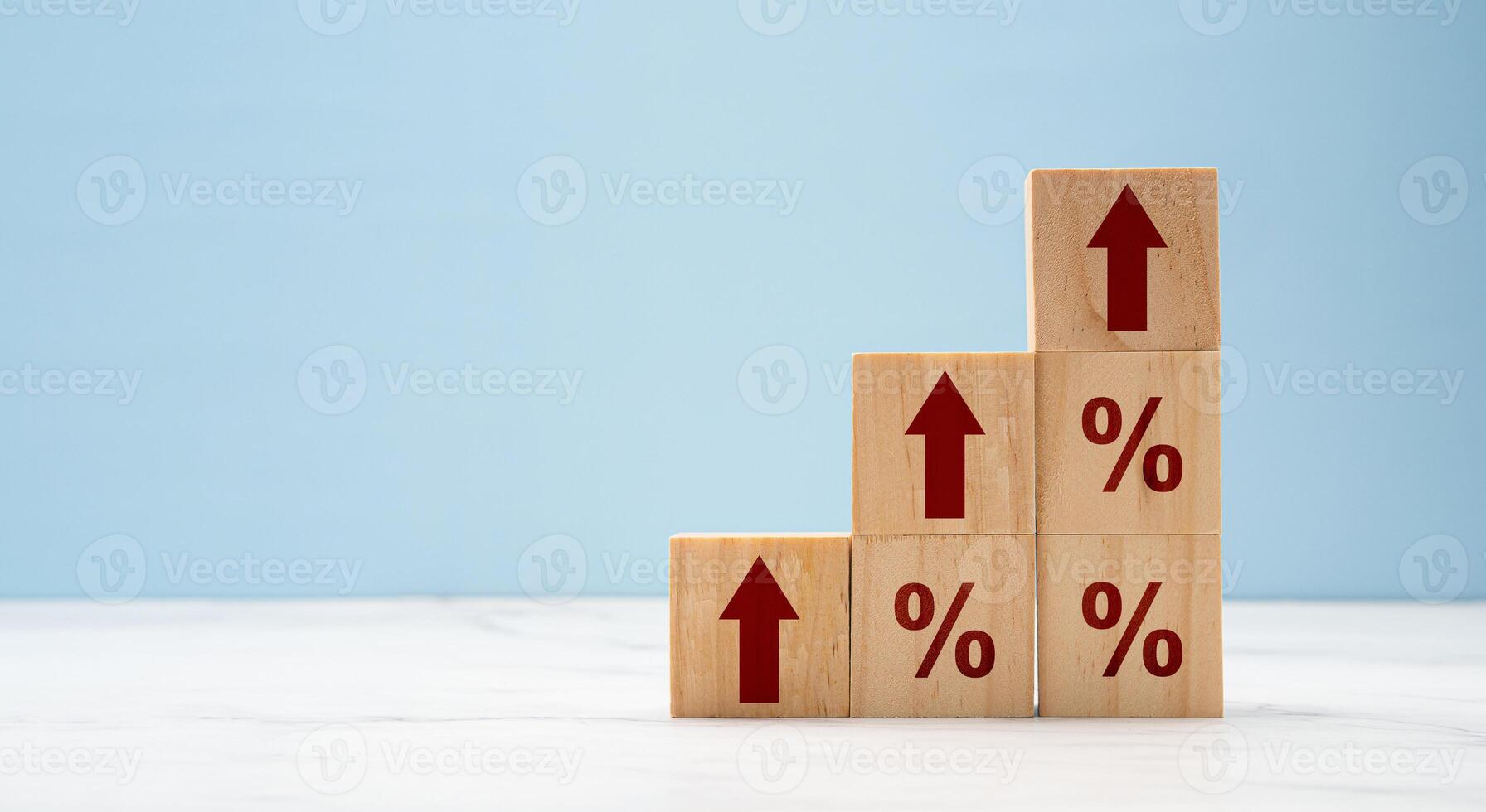 Wooden cubes with red arrows up and percent symbols on marble with a light blue background photo