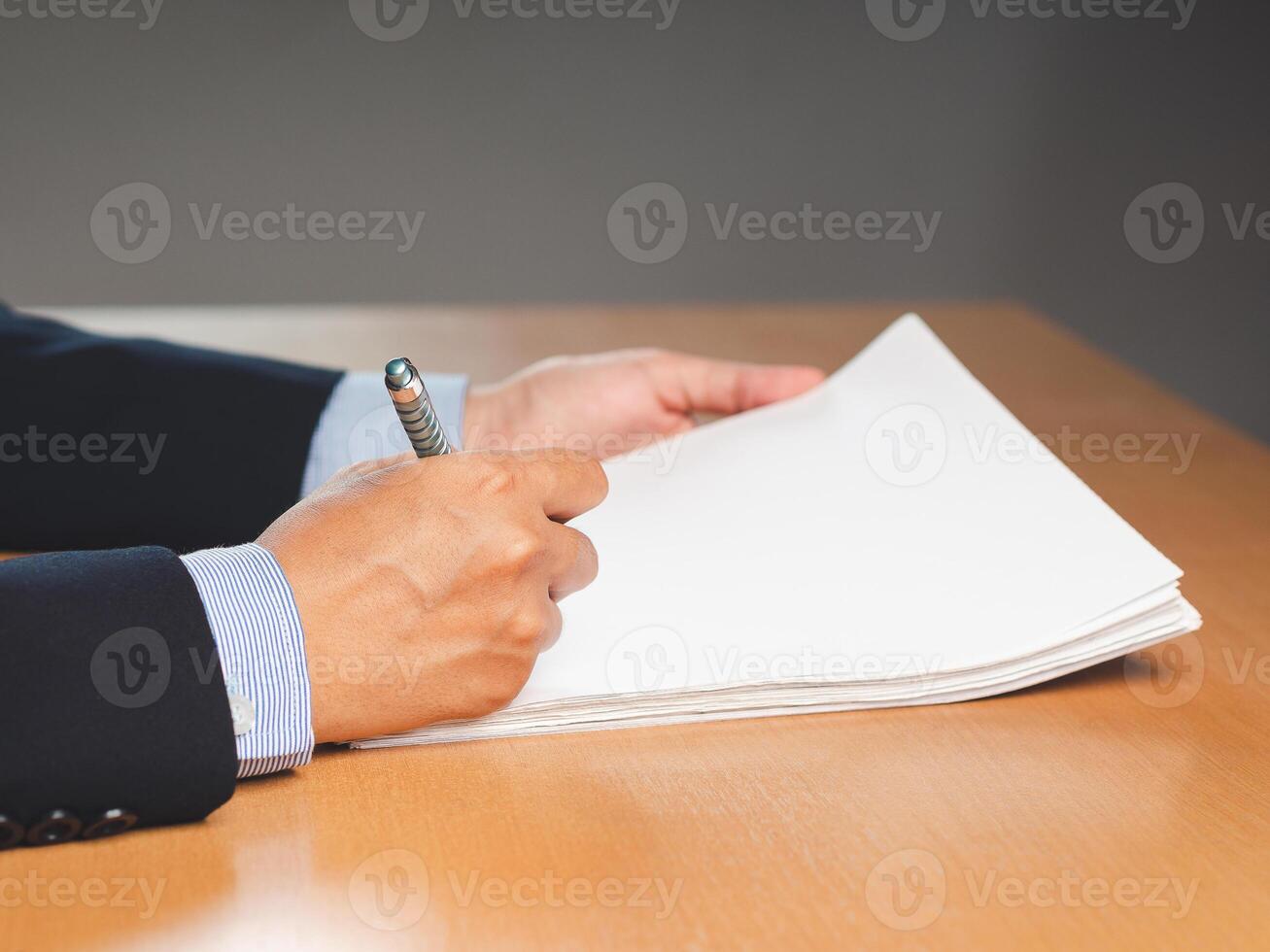 Close-up of a businessman signing on documents while sitting working in the office photo
