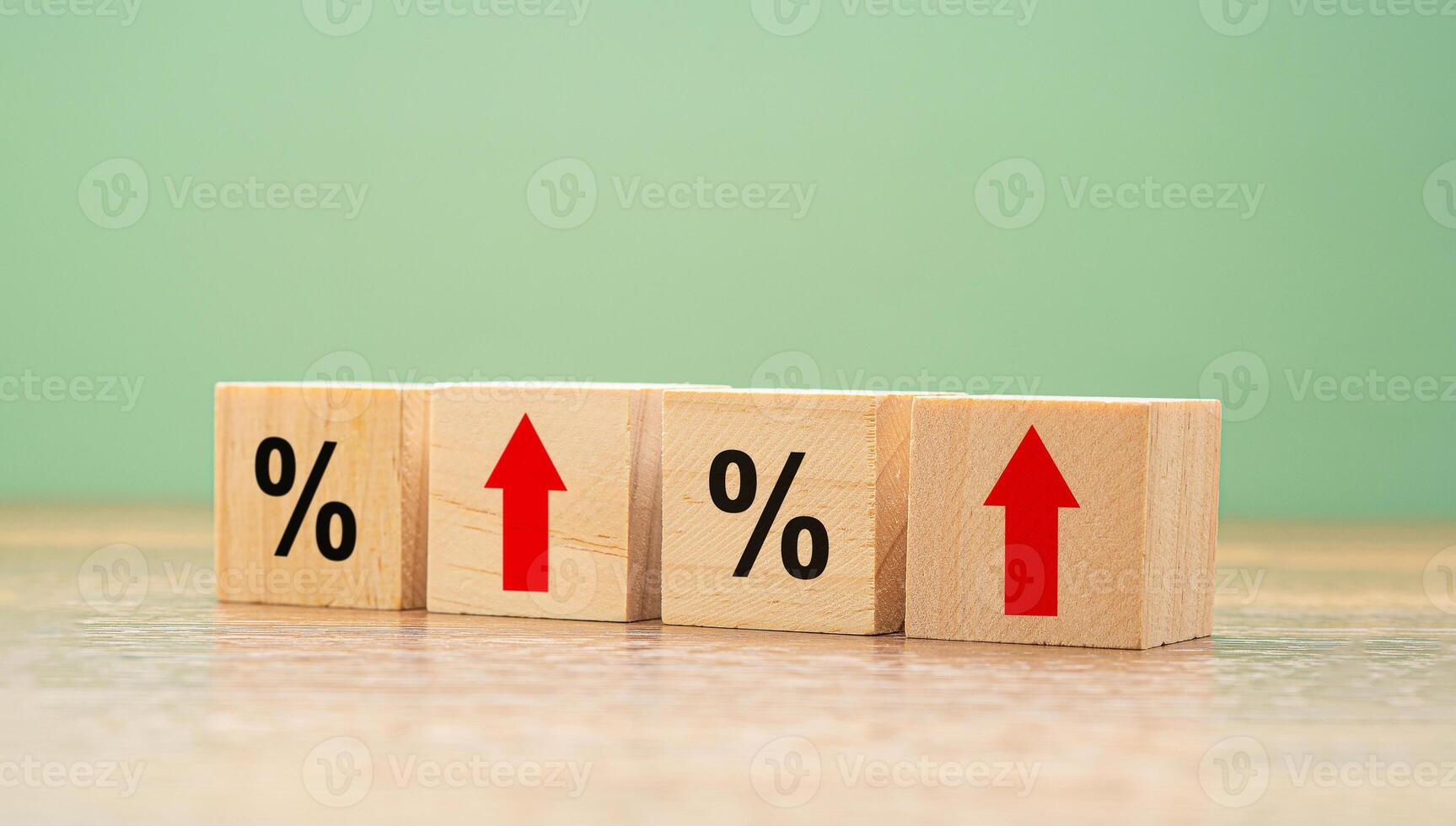 Wooden cubes with red arrows and percent symbols on a wooden table with a green background photo