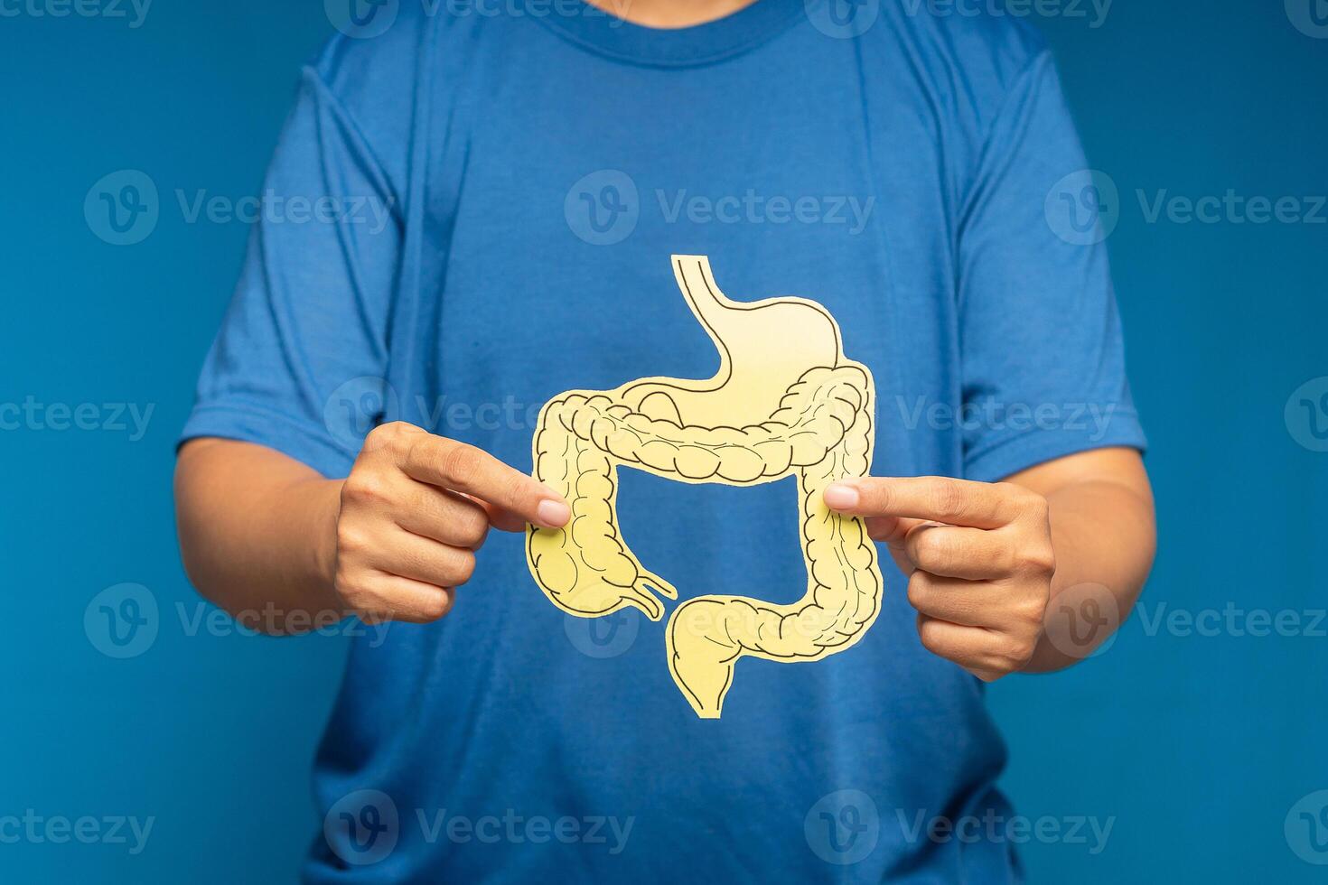 Close-up of hand holding a colon symbol while standing on a blue background photo
