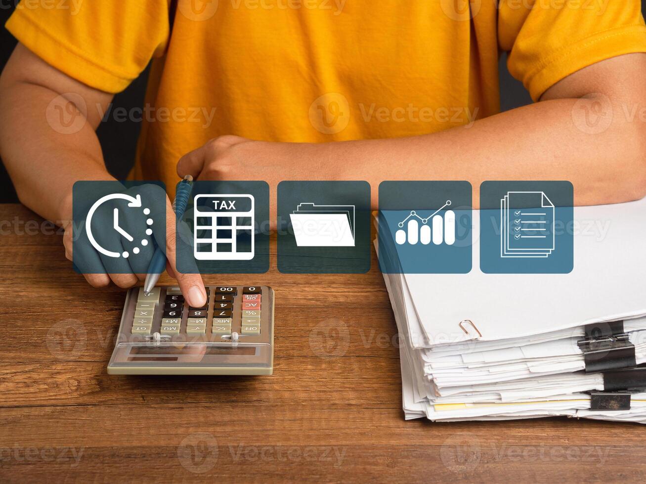Tax day concept. A young man in an orange casual using a calculator to calculate taxes while sitting in the office photo