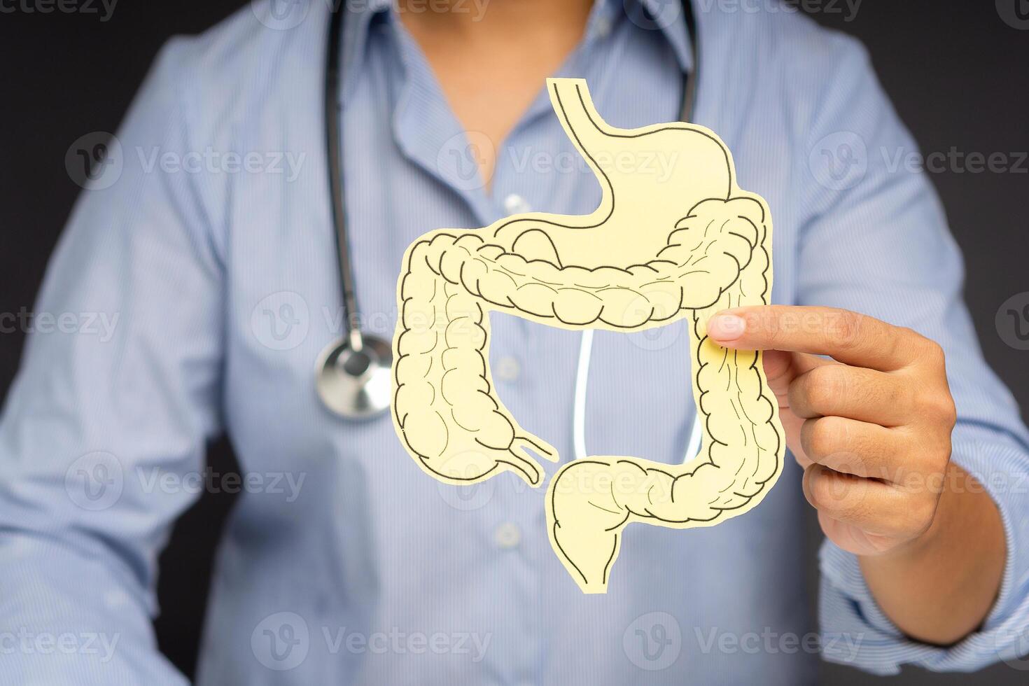Hand of the doctor holding a colon symbol while standing on a gray background photo