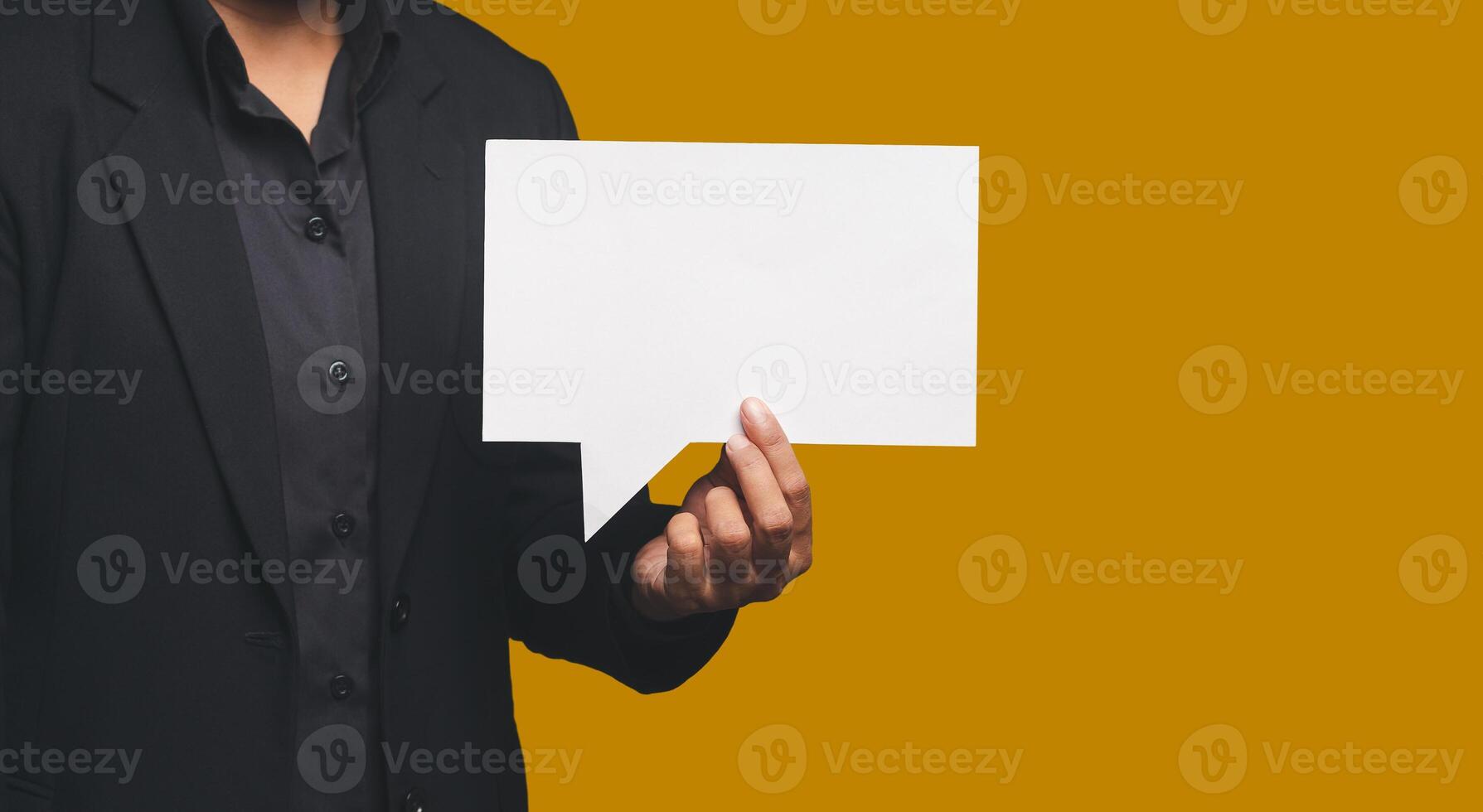 Close-up of hand businessman in a suit holding a blank white speech bubble while standing on an orange background photo