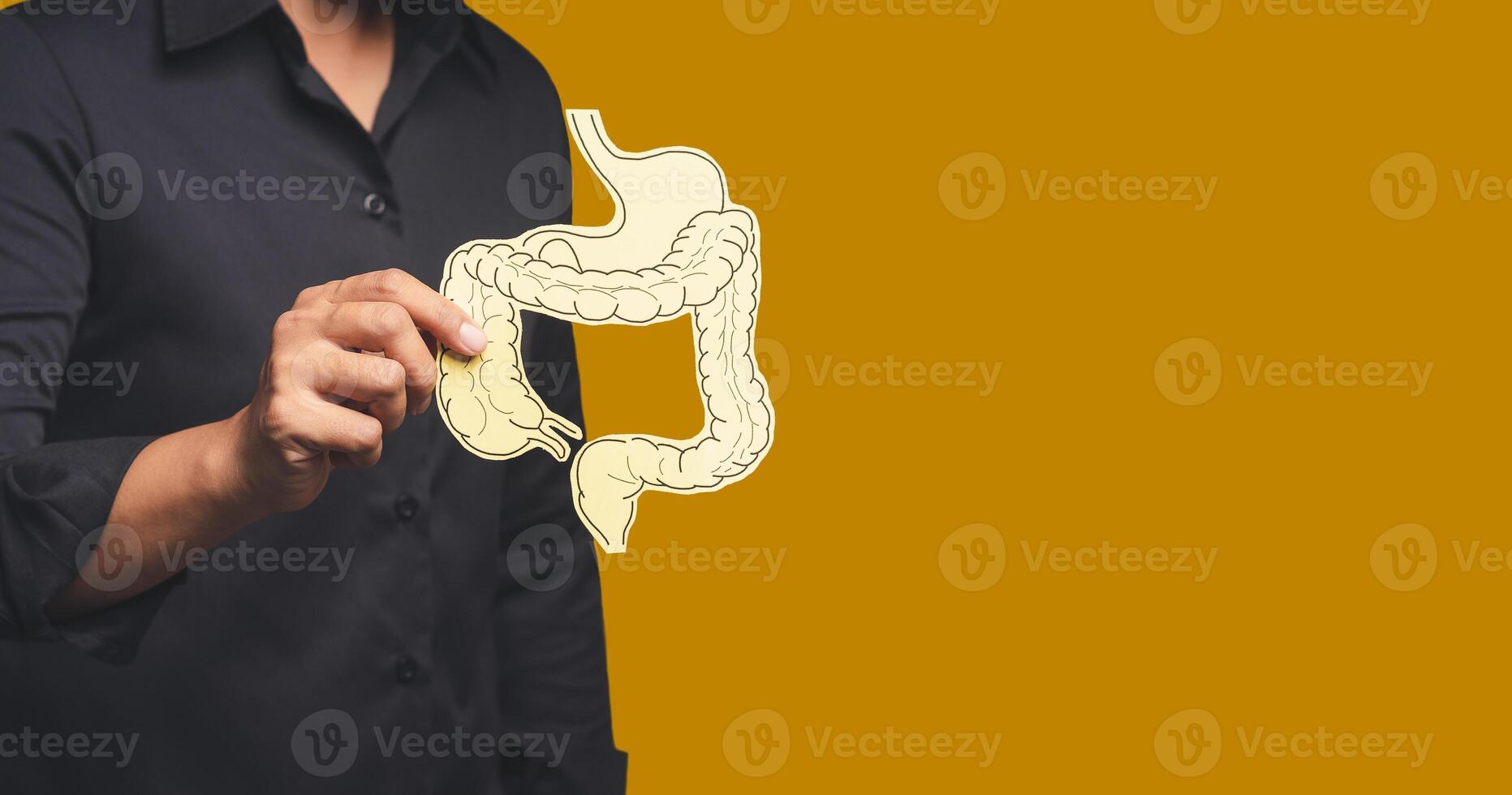 Close-up of hand holding a colon symbol while standing on an orange background photo