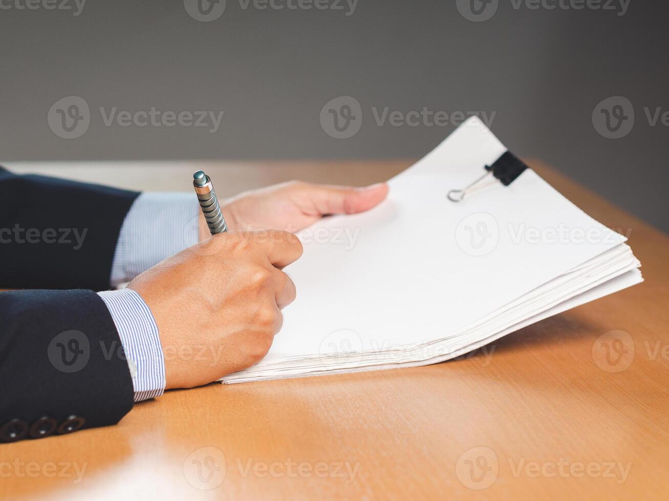 Close-up of a businessman signing on documents while sitting working in the office photo