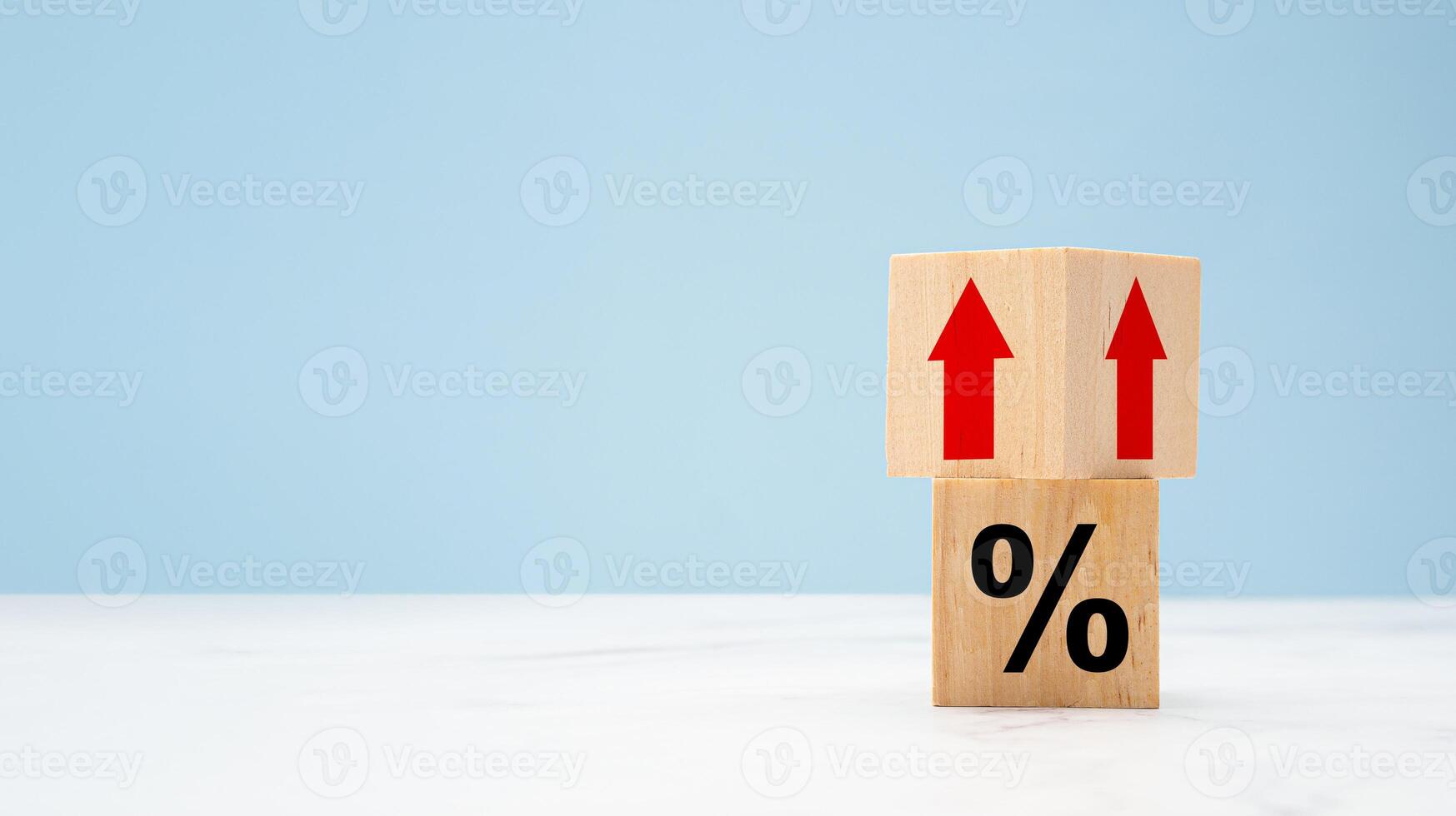 Wooden cubes with red arrows up and percent symbols on marble with a light blue background photo