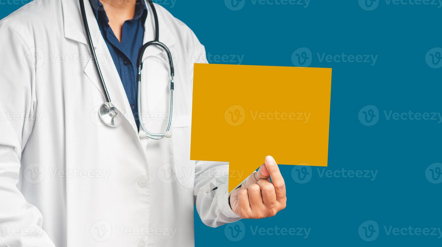 Doctor in uniform holding an orange blank speech bubble while standing on a blue background photo