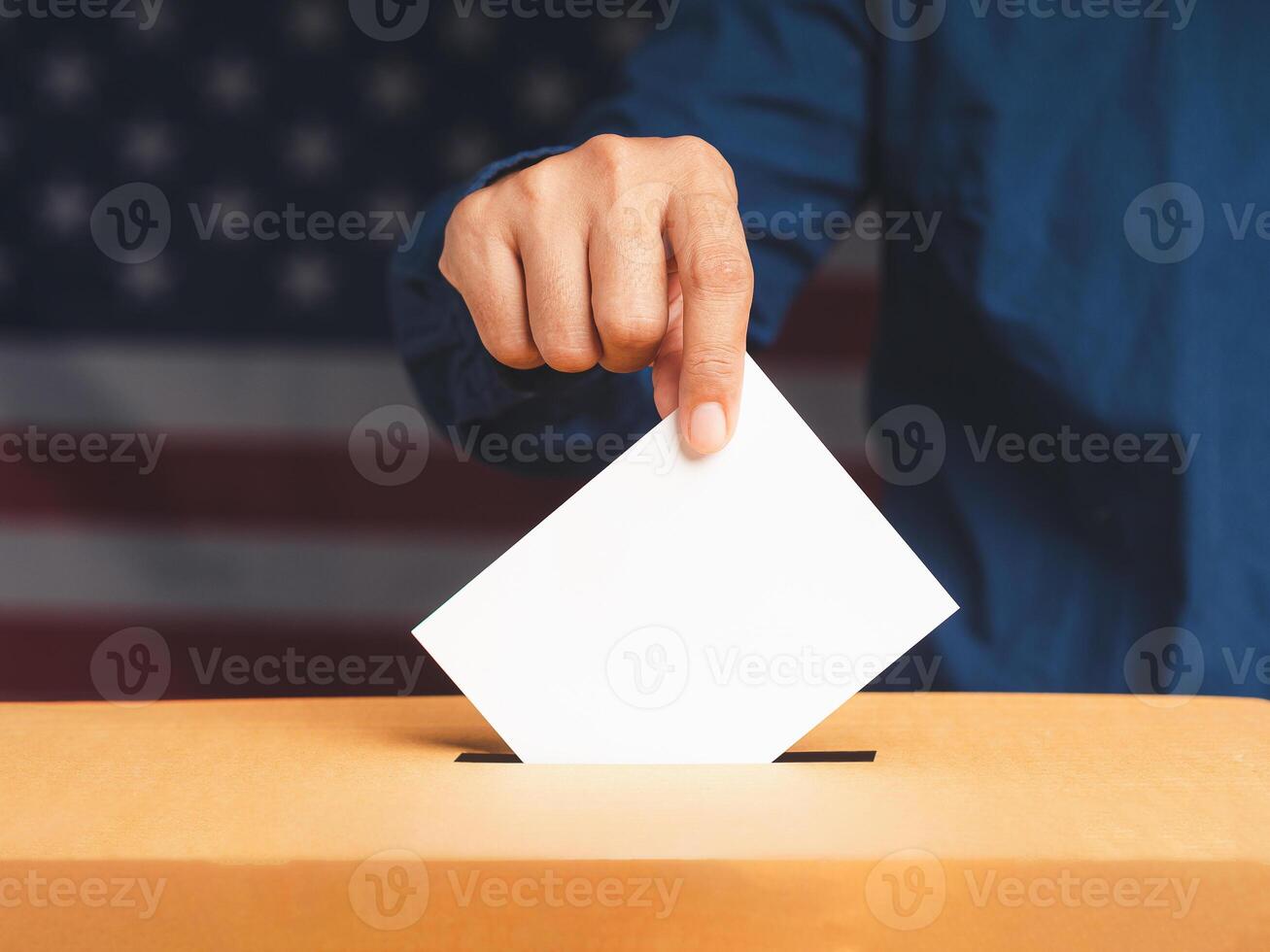 Hand voter holding ballot paper putting into the voting box at place election with an American flag background photo