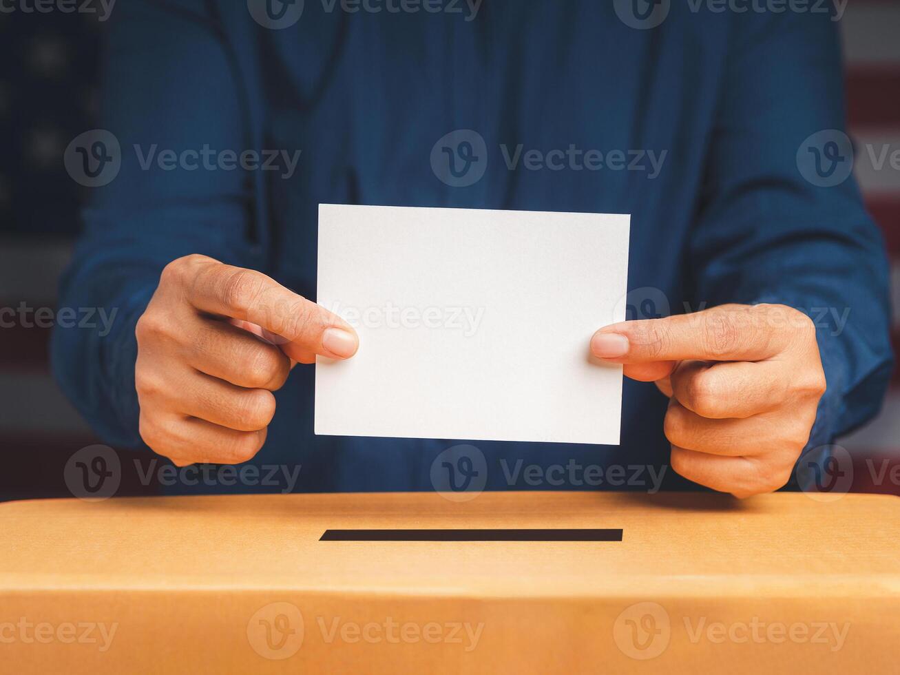 Hands voter holding ballot paper putting into the voting box at place election with an American flag background photo