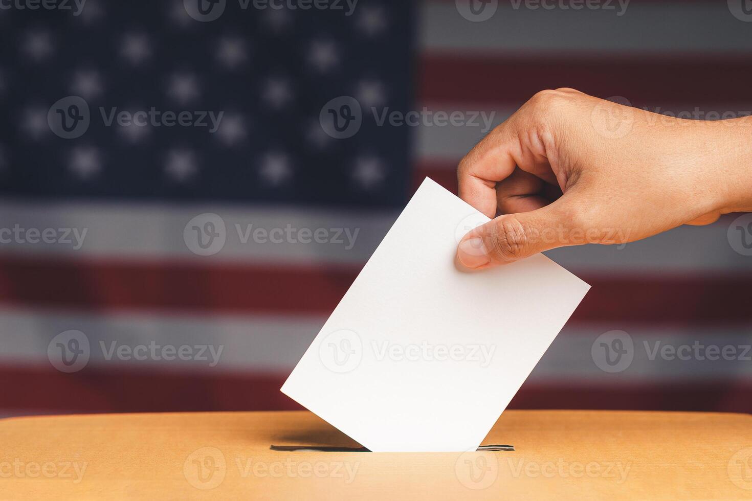 Hand voter holding ballot paper putting into the voting box at place election with an American flag background photo