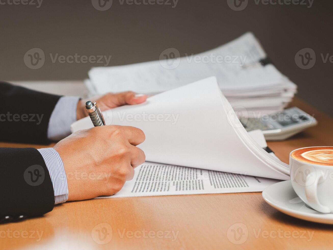 Close-up of a businessman signing on documents while sitting working in the office photo