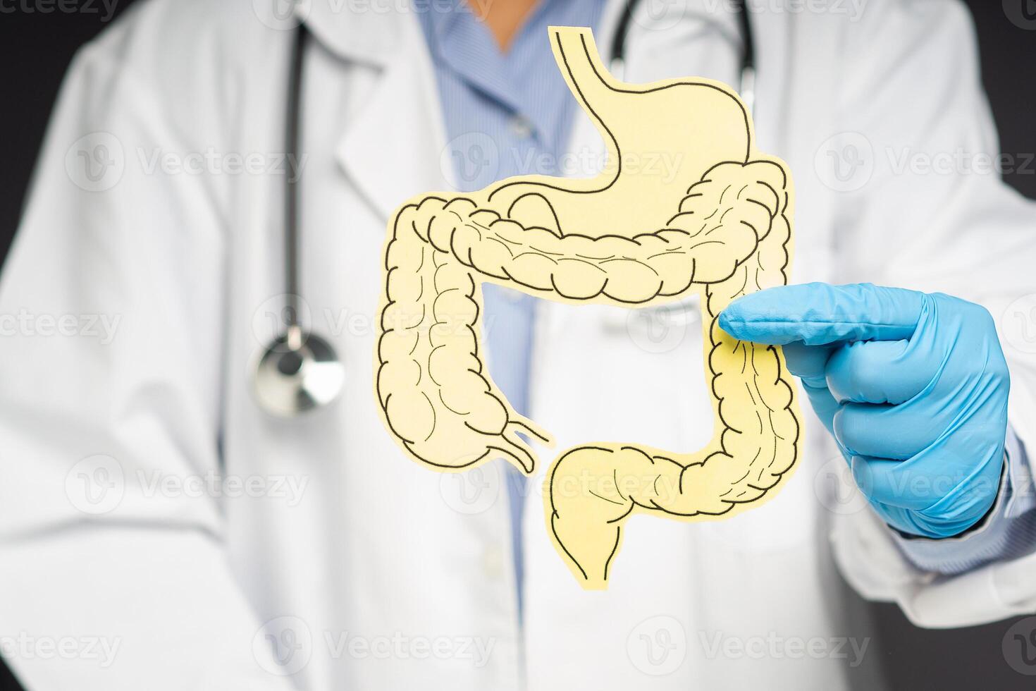 Hand of the doctor holding a colon symbol while standing on a gray background photo