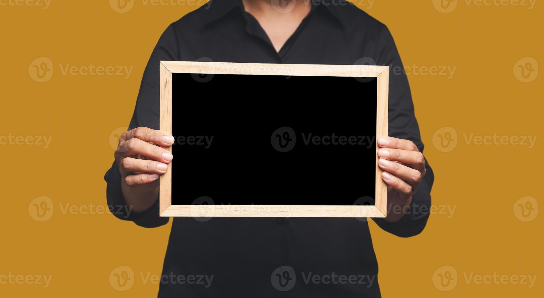 Close-up of hands holding a blank mini blackboard while standing on an orange background. Space for text photo