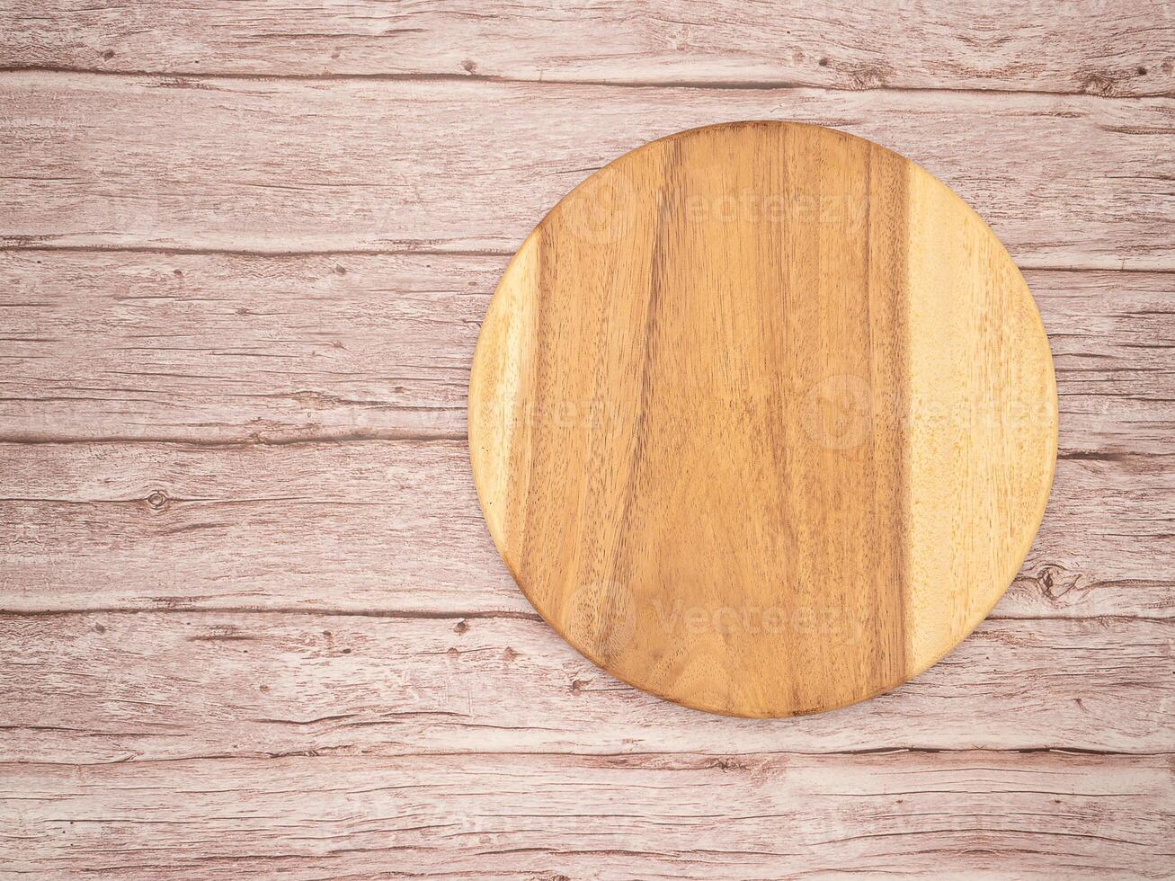 Top view of a blank round wooden cutting board over a wooden table photo