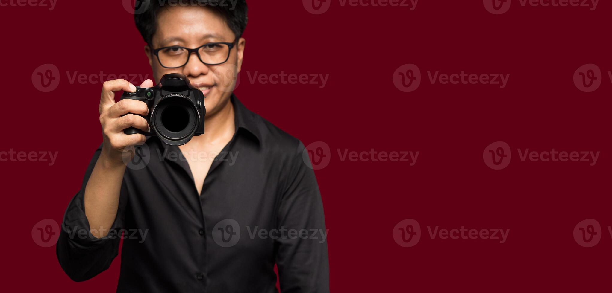 Photographer with a camera. Tomboy's holding the digital camera while standing on a red background photo