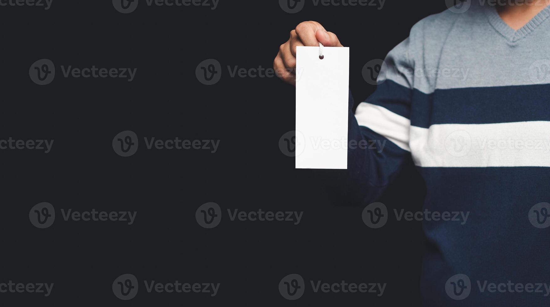 Hand holding a blank white label or price tag while standing on a black background photo