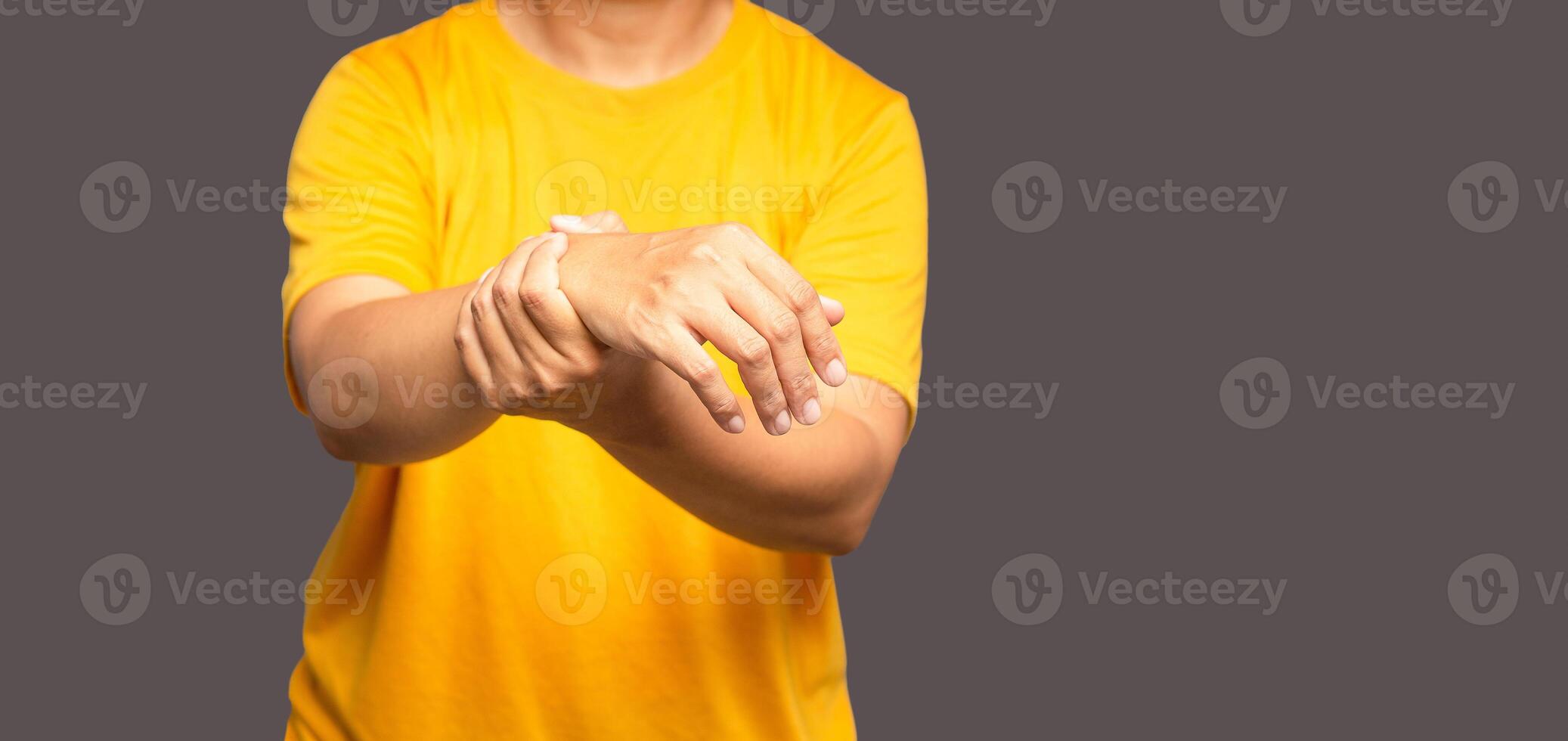 Close-up of hands young man suffering from wrist pain while standing on a gray background photo