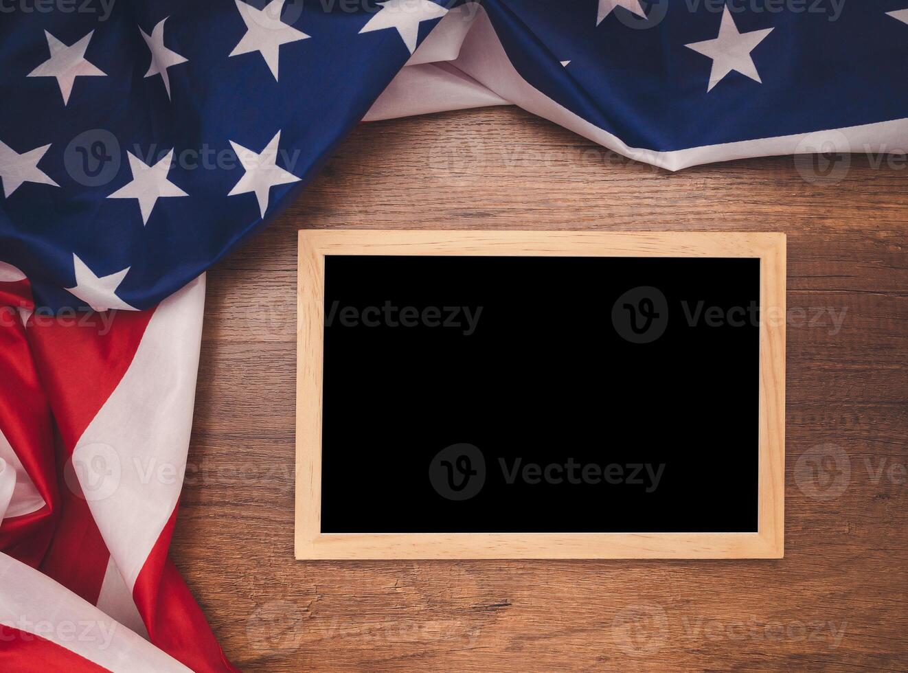 Top view of the American flag and empty blackboard over a wooden table photo