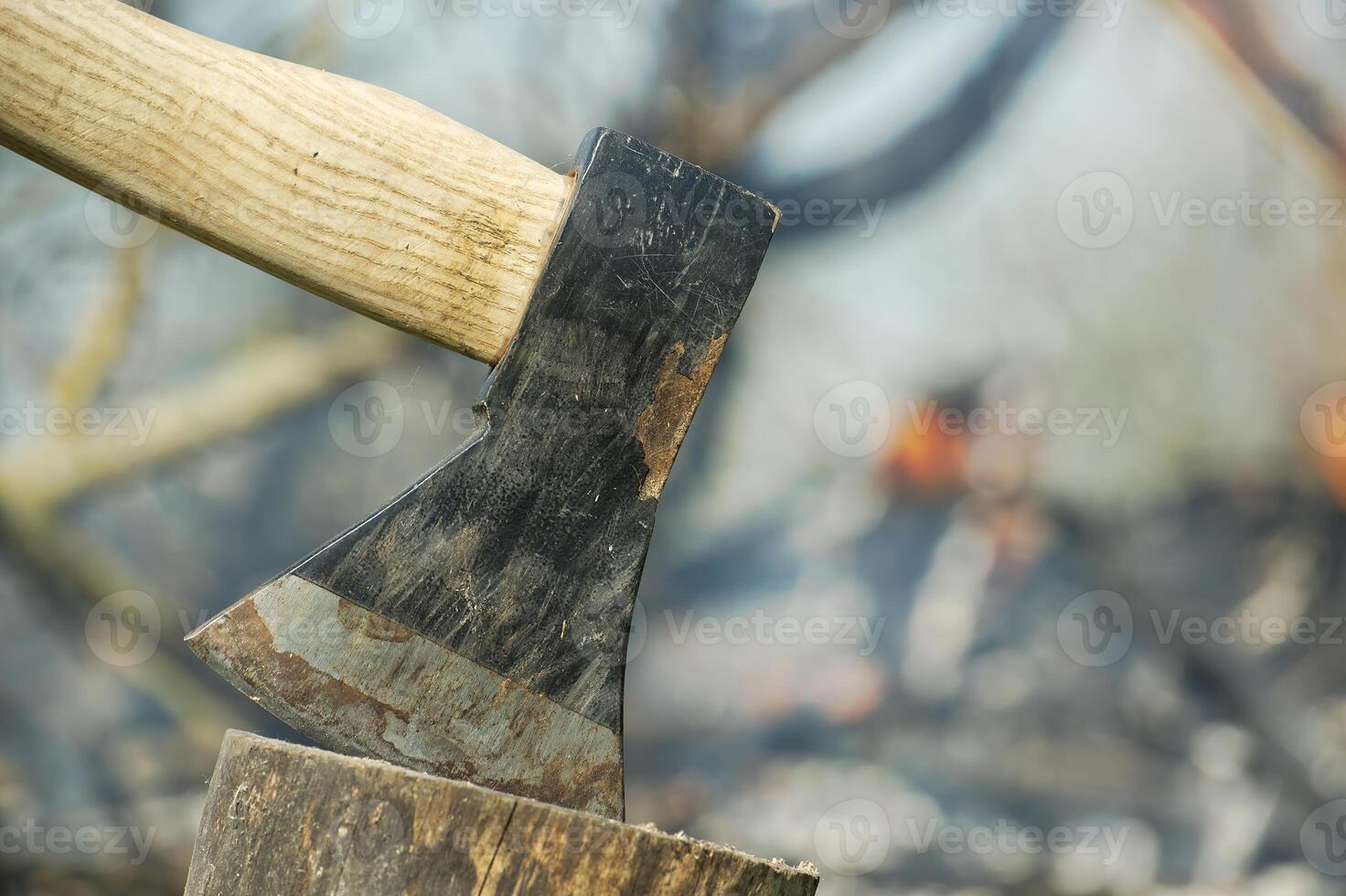 Close up of axe with a black blade stuck in a log photo