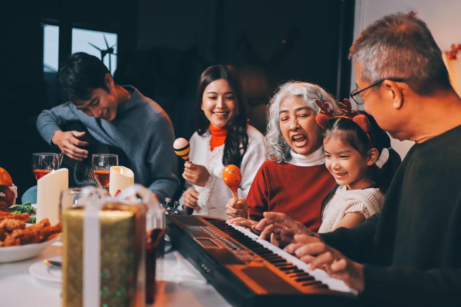 Multi-Generation Family Celebrate Christmas At Home Wearing Santa Hats And Antlers Opening Presents photo