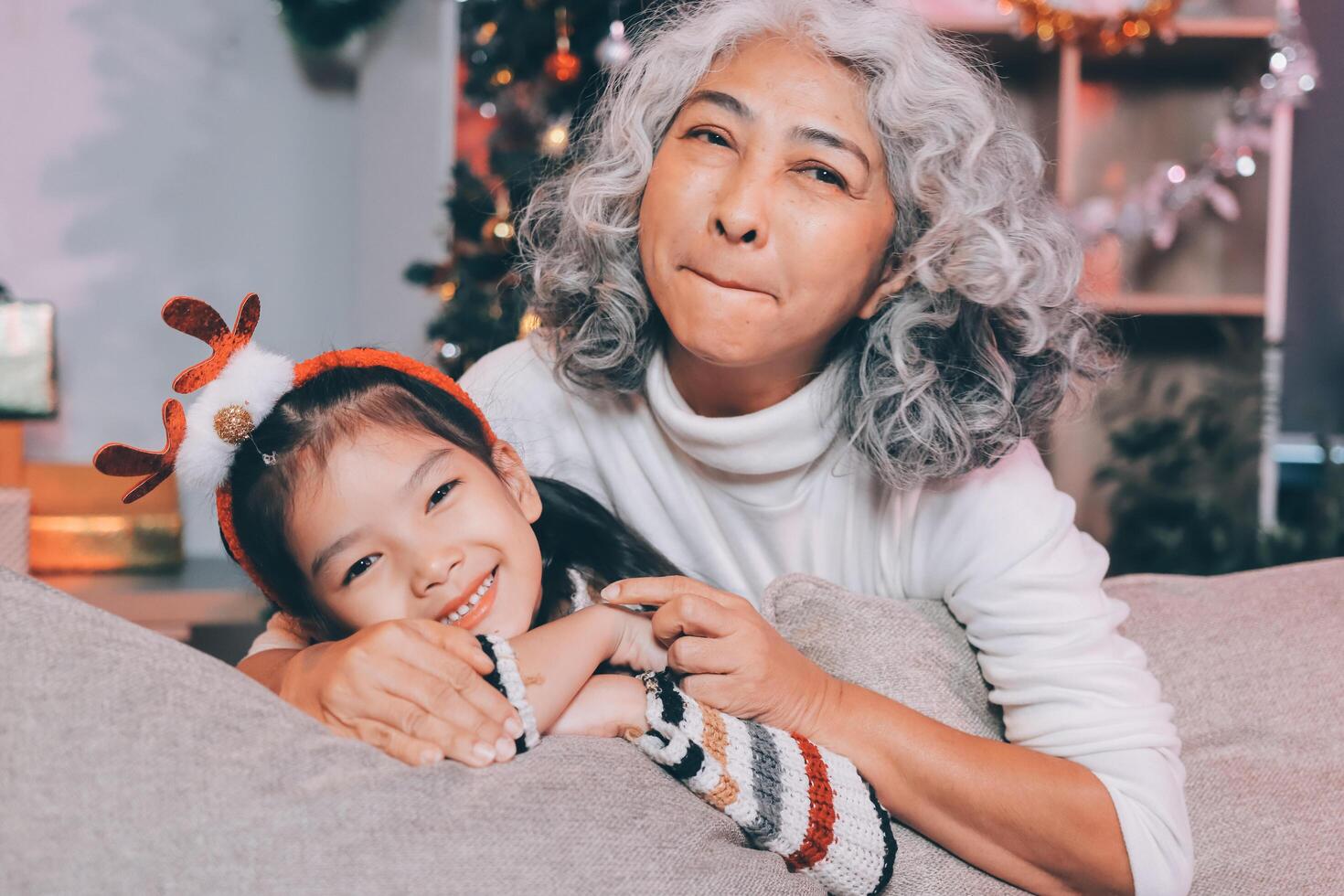 Happy family on Christmas morning. Affectionate grandmother and cheerful granddaughter open a holiday gift together at home photo