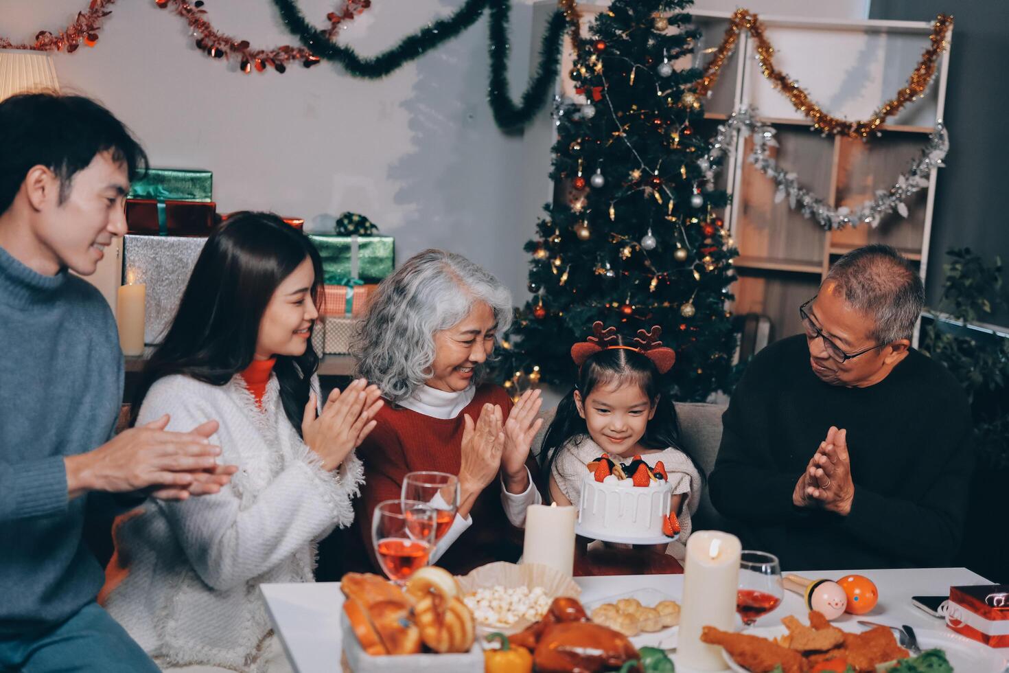 Multi-Generation Family Celebrate Christmas At Home Wearing Santa Hats And Antlers Opening Presents photo